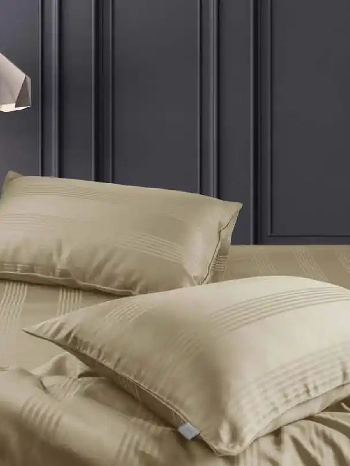Two sand beige satin stripe pillow covers on the matching bedding, close-up