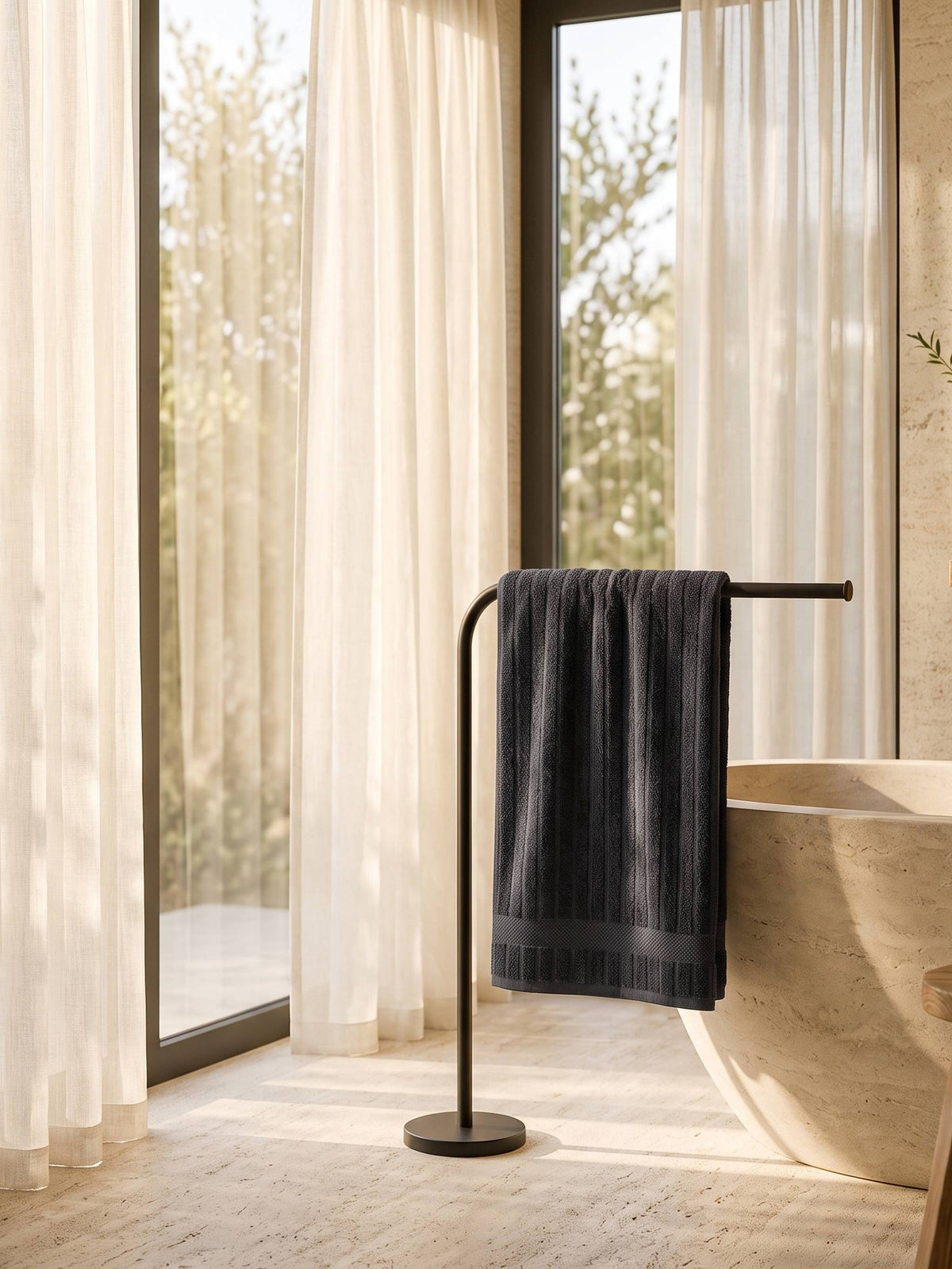 Charcoal cotton towel on a floor-standing rail beside a stone bath