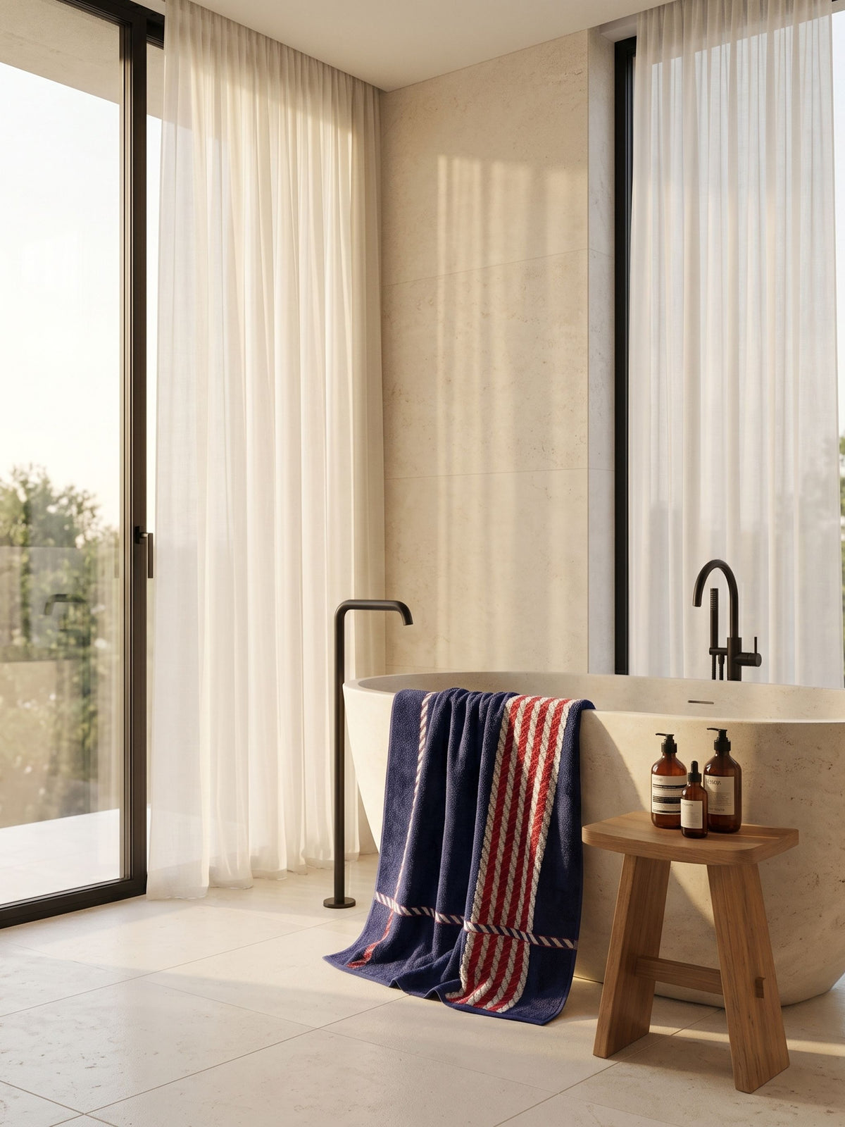 Navy striped cotton towel over a wooden stool beside a stone bath