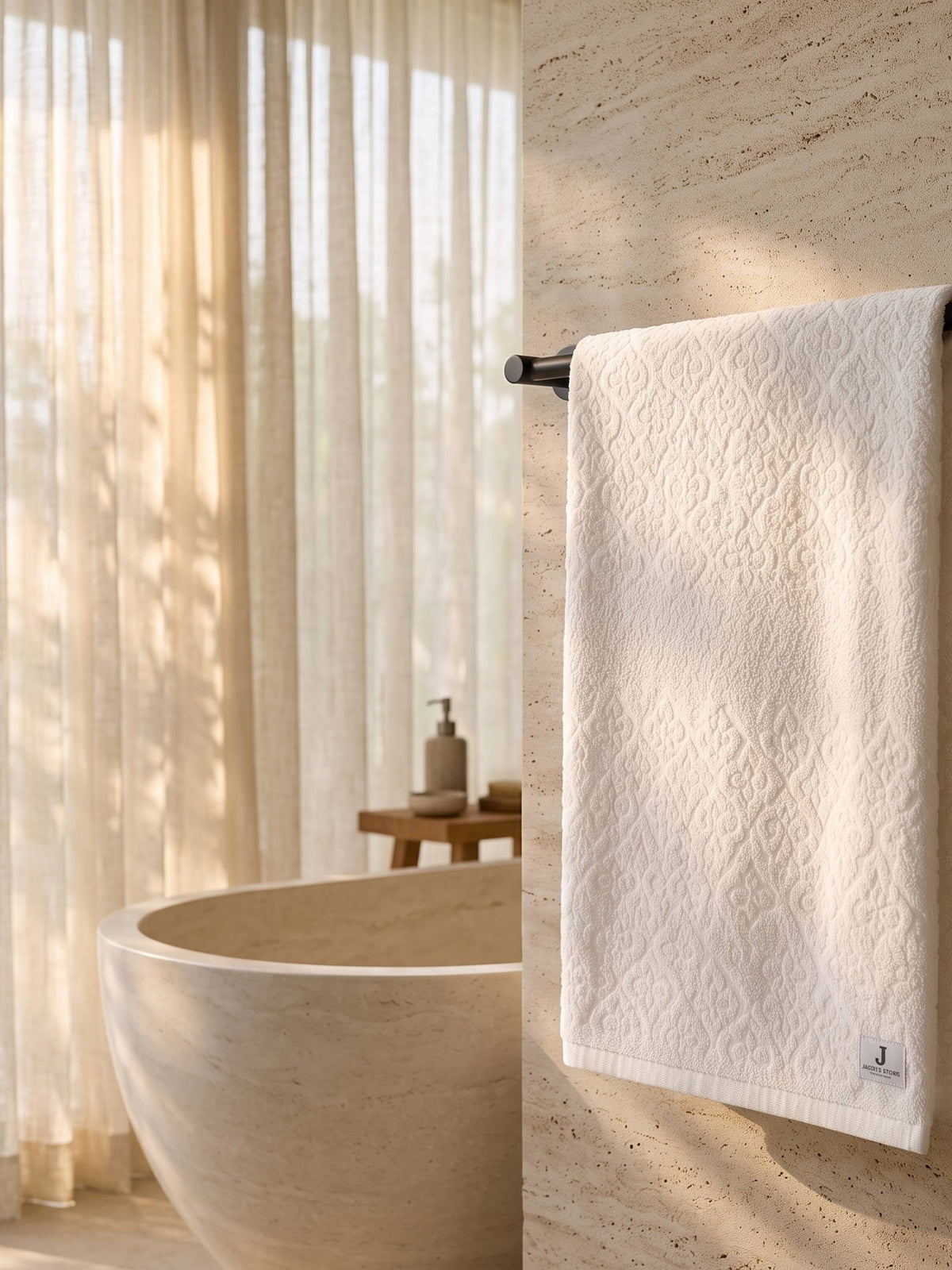 White cotton bath towel with an all-over floral damask pattern folded on a wooden bathroom shelf.