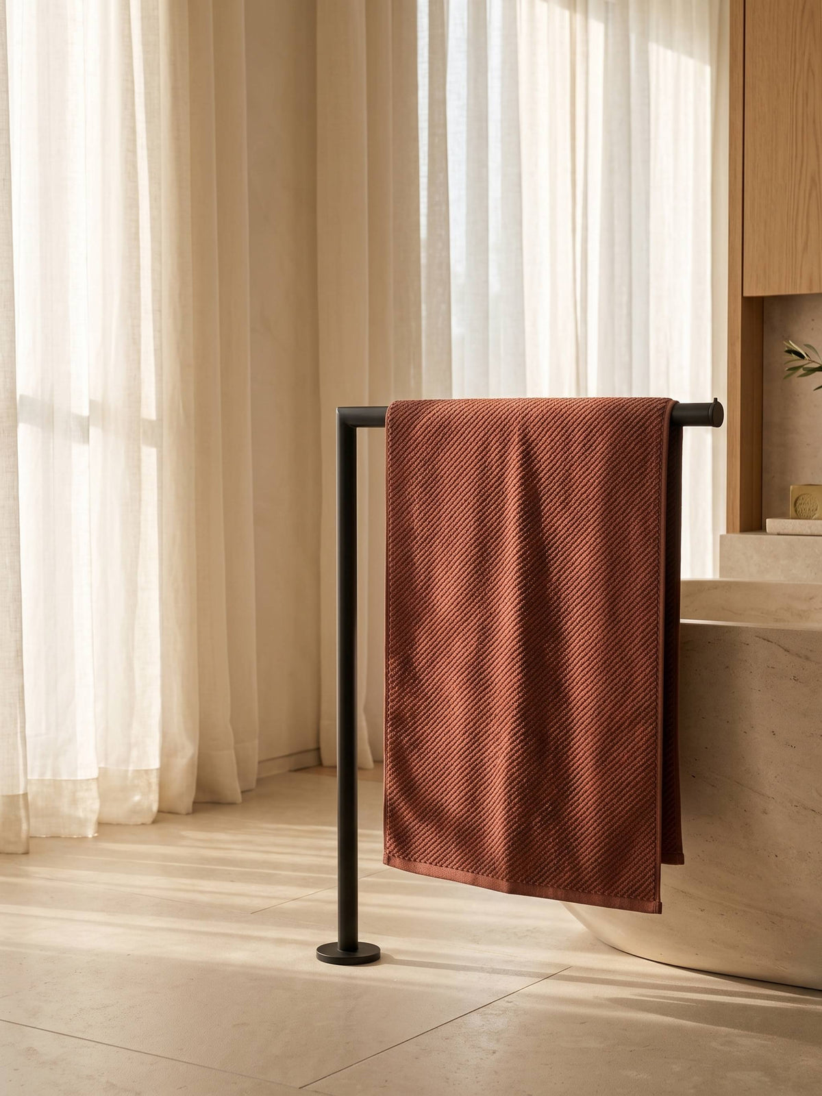 Brown plain cotton bath towel folded on a wooden bathroom 