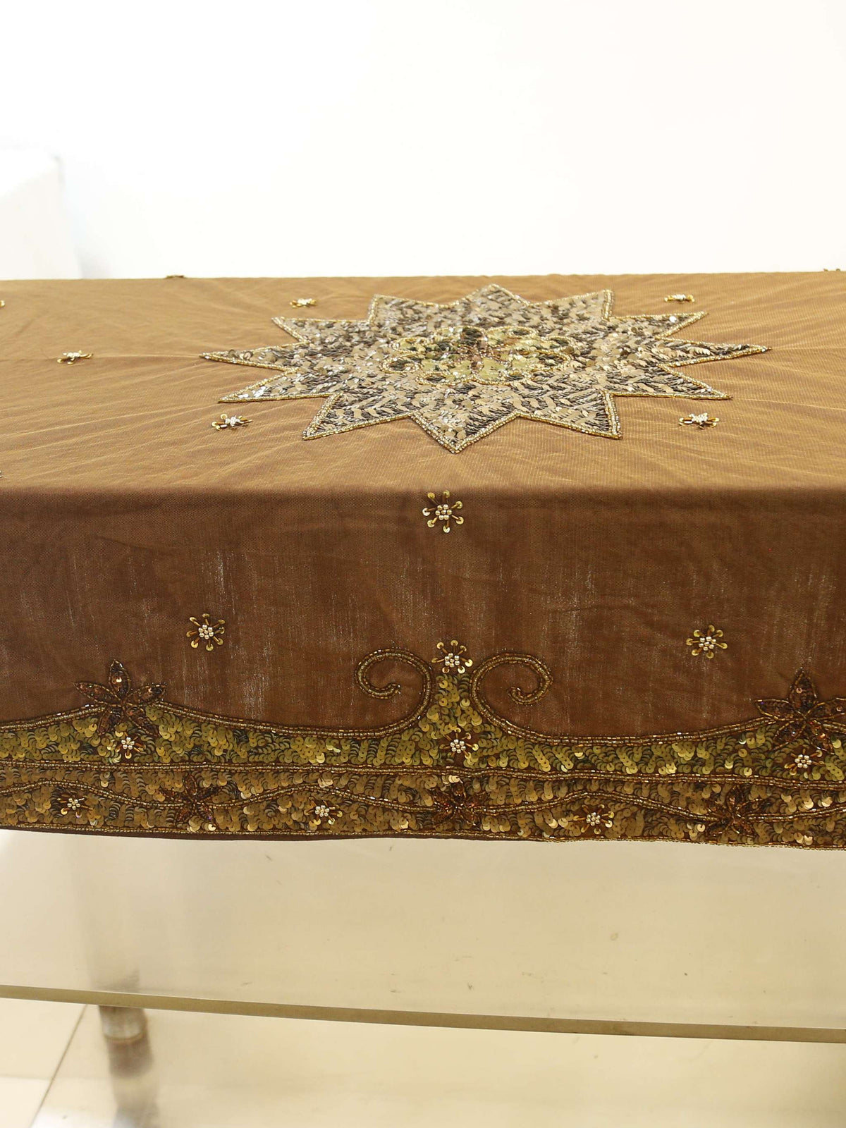 Brown velvet table cover with a silver sequinned star medallion at the centre and a gold-green sequinned scalloped border