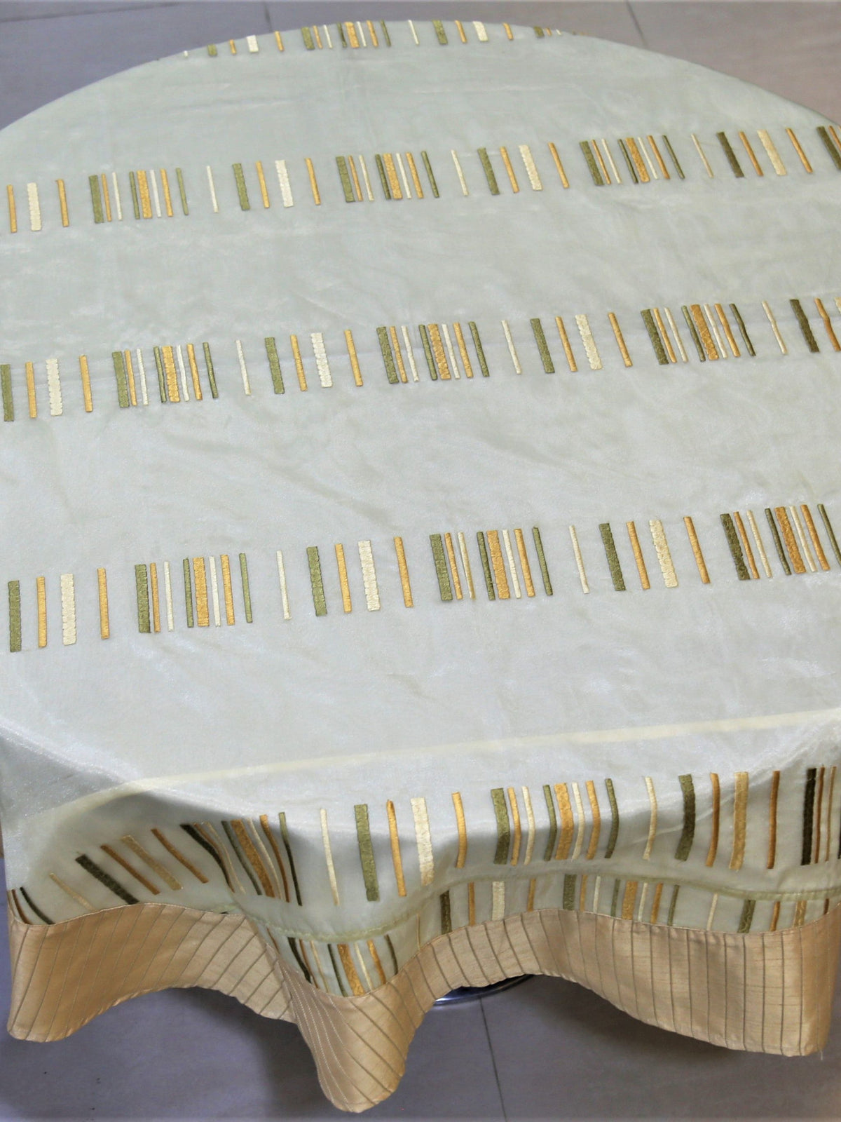 Round pale gold table cover with embroidered multicolour vertical dash stripes and a tan striped border