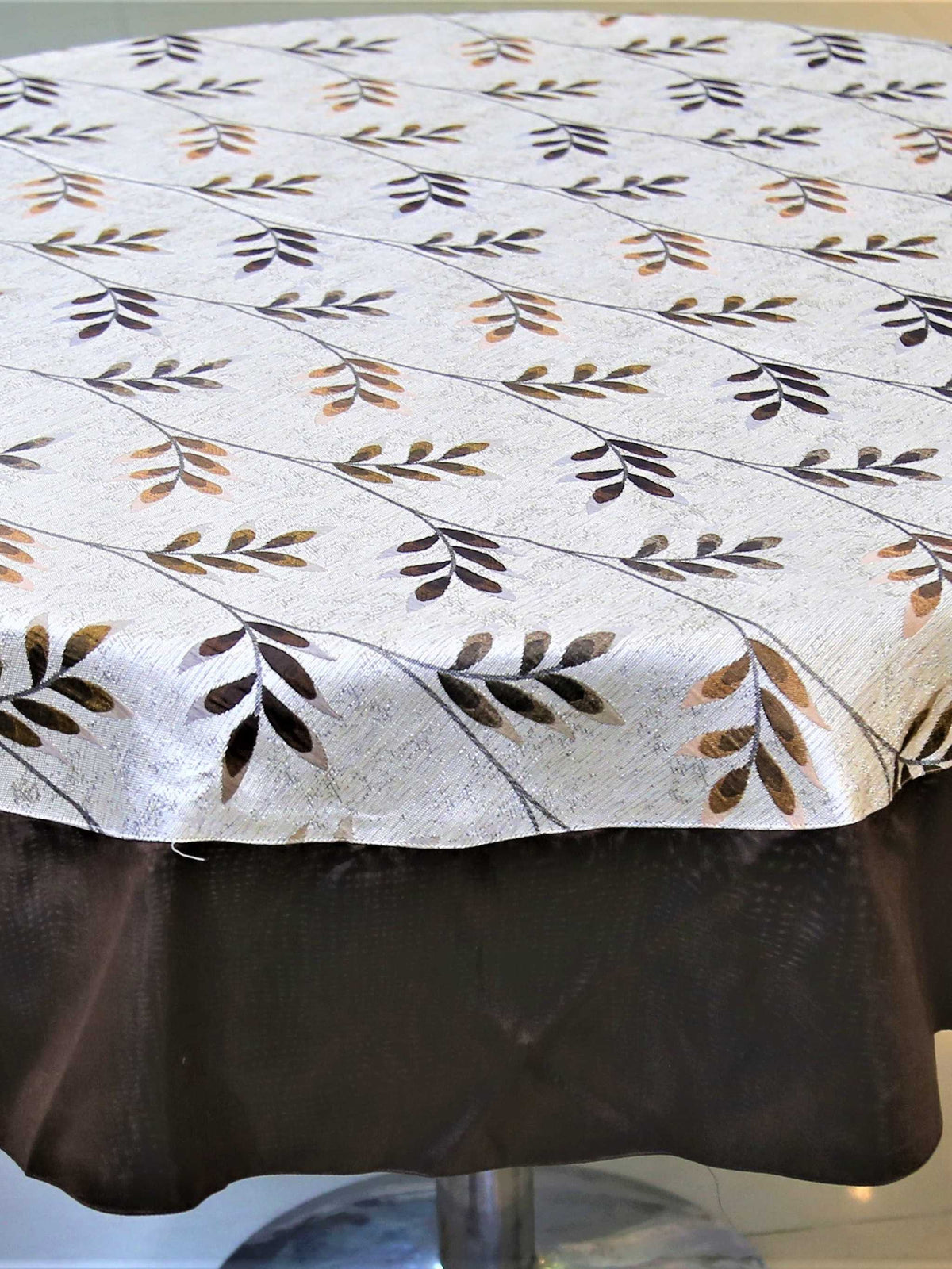 Round white table cover with a beige-brown leaf-vine print and a solid dark brown underskirt