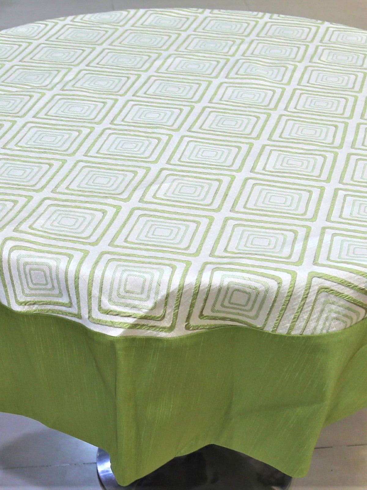 Round table cover with a cream geometric diamond print on top and a solid olive-green underskirt