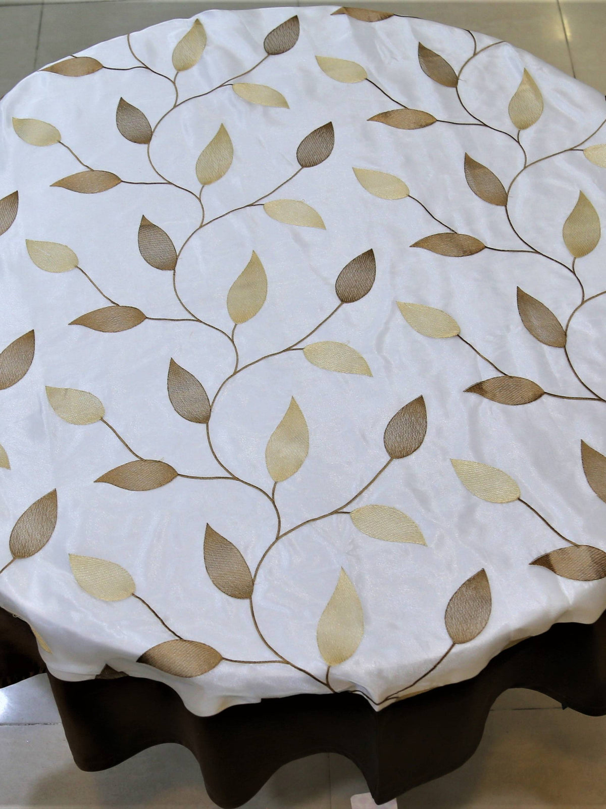 Round cream table cover with a beige-gold embroidered leaf-vine pattern and a solid dark brown underskirt