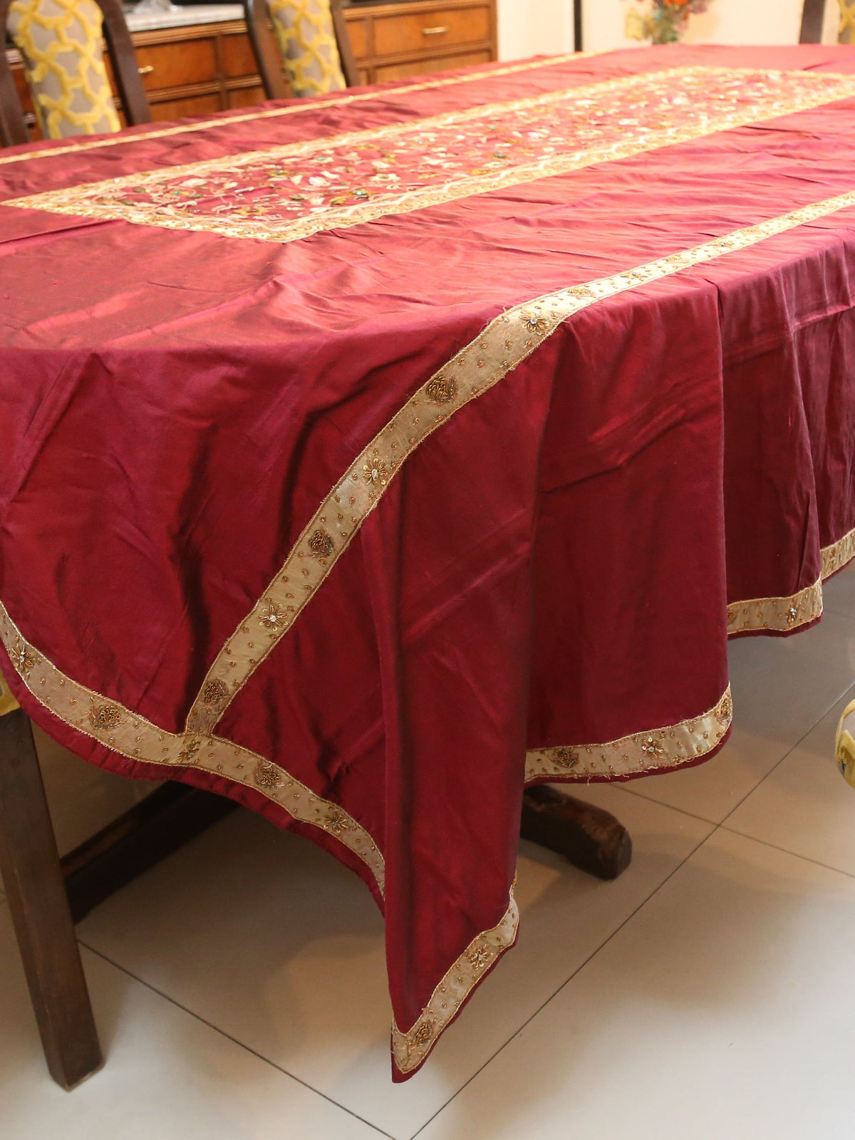 Maroon silk table cover with a gold-bordered floral embroidered runner panel down the centre