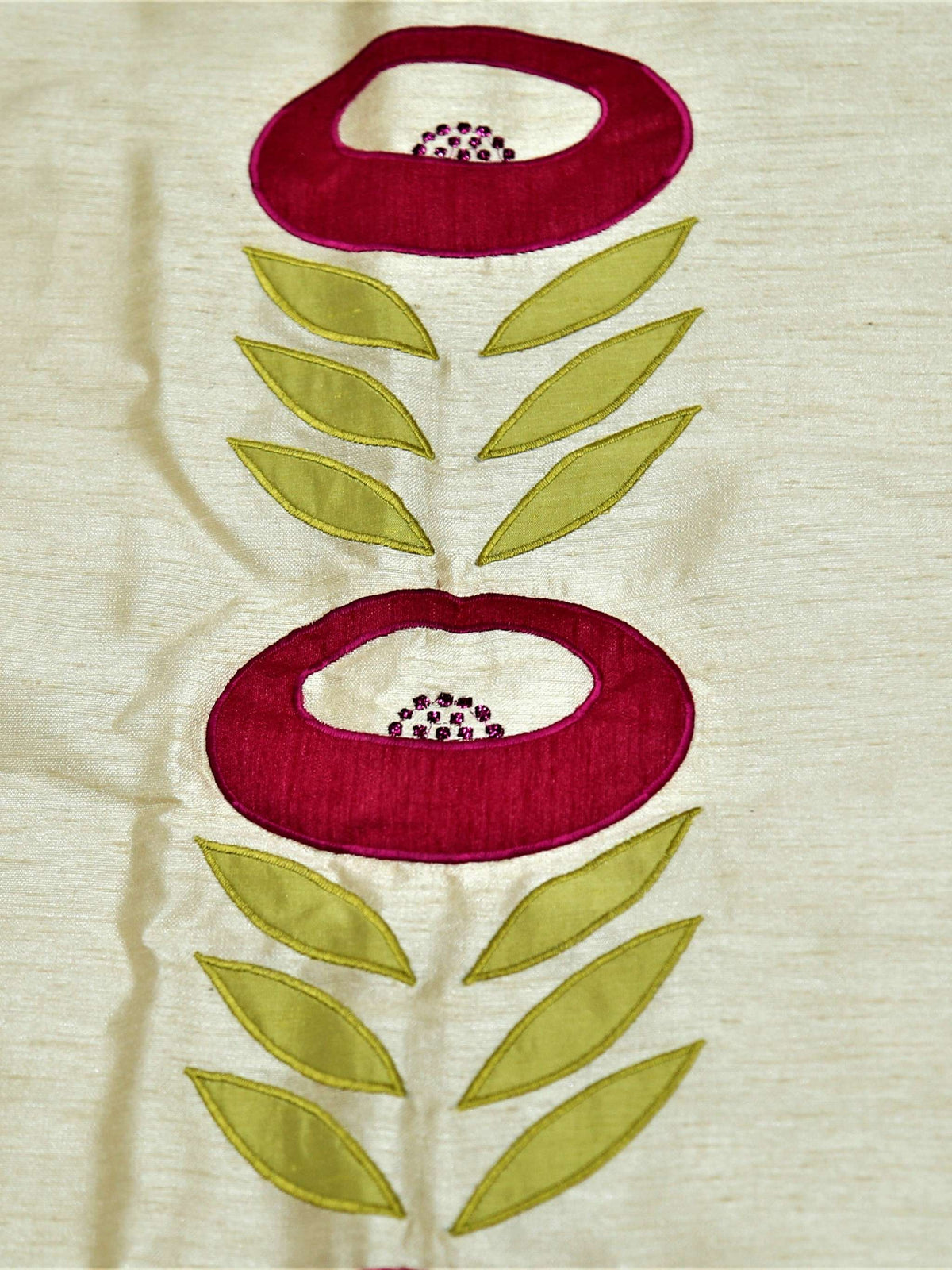 Close up of the cream fabric with a crimson and green embroidered flower on a stem