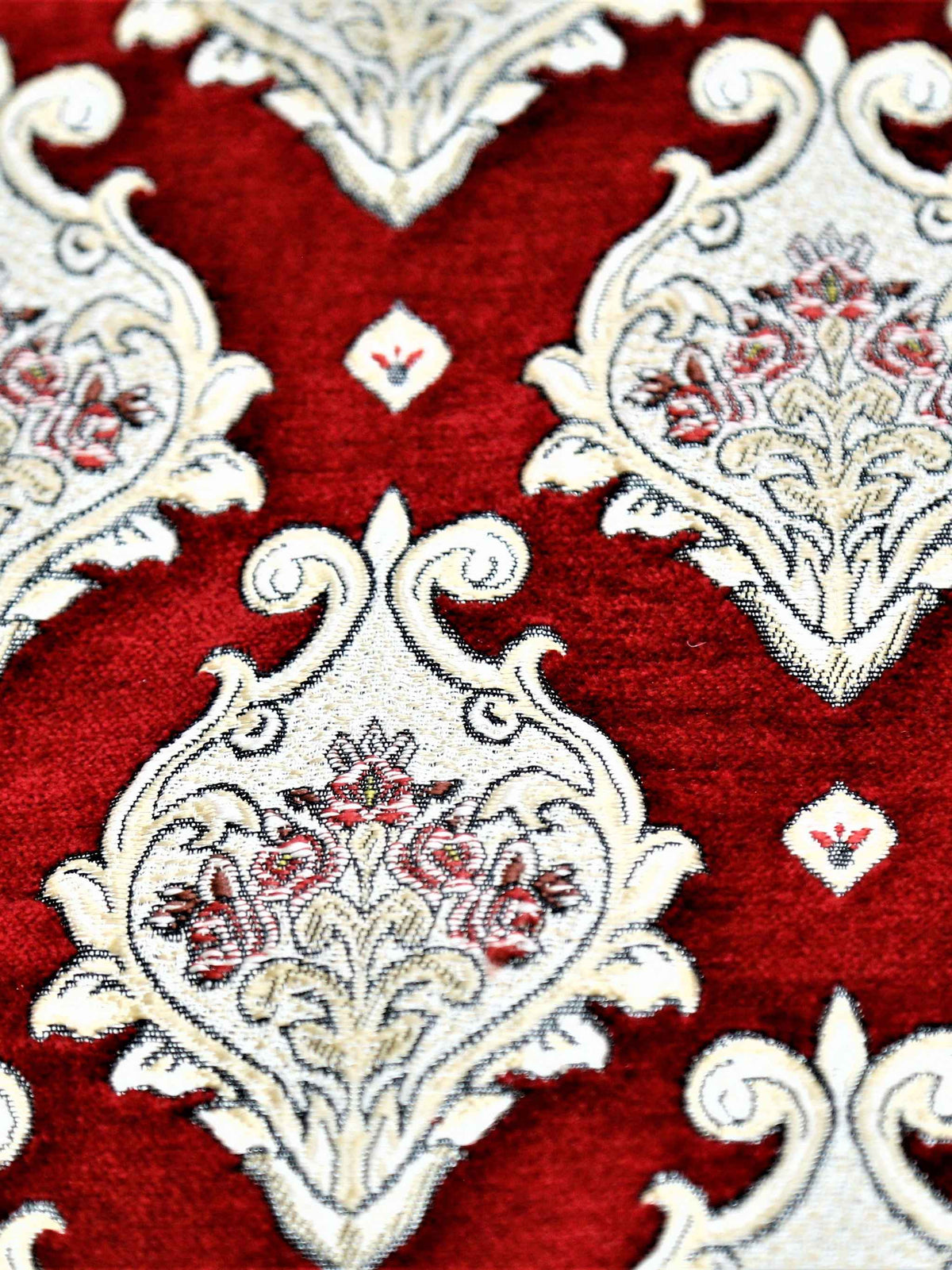Close up of deep red fabric with cream damask medallions and fine floral fill