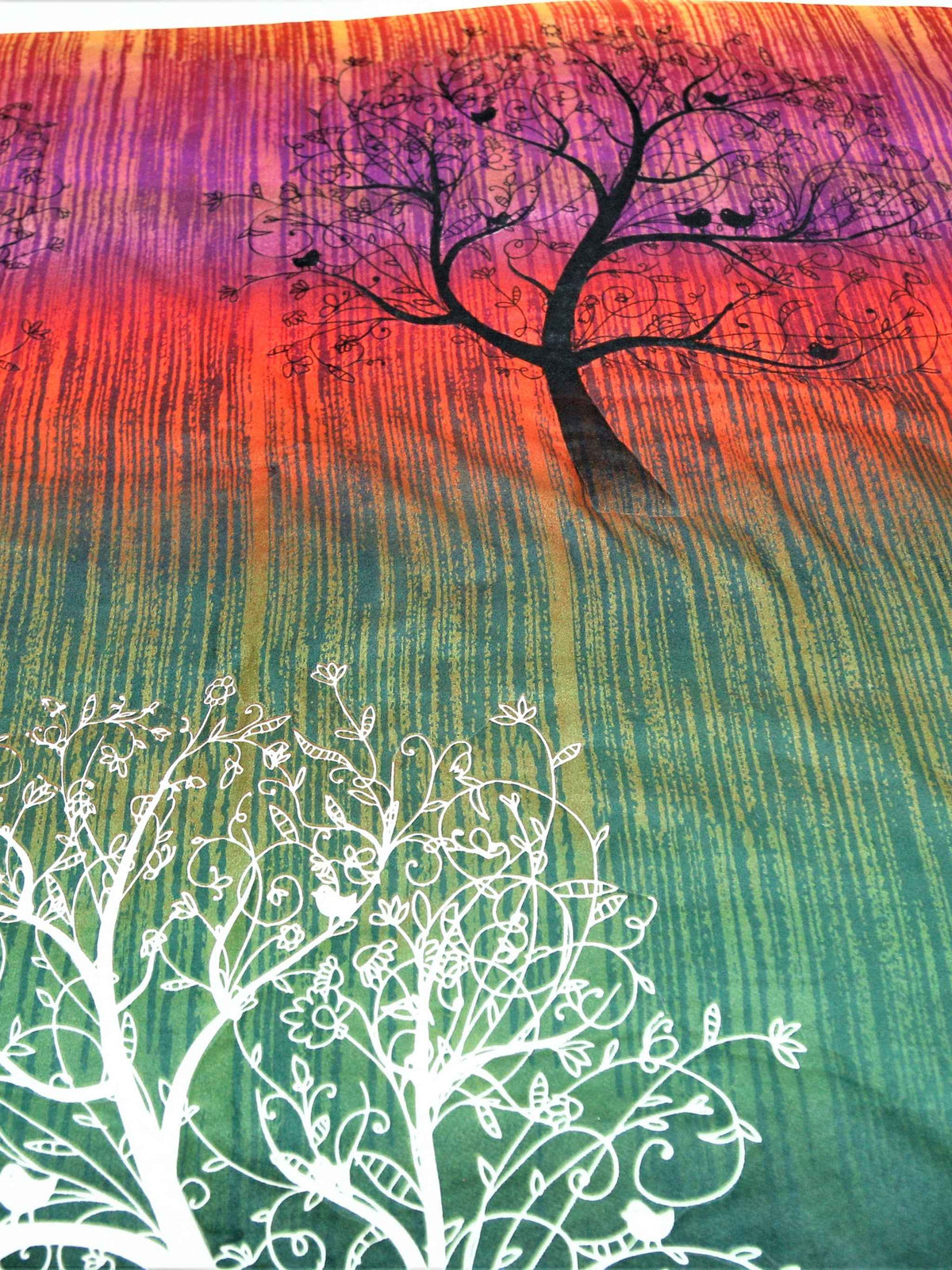 Close-up of white tree print on orange to green ombre striped cotton