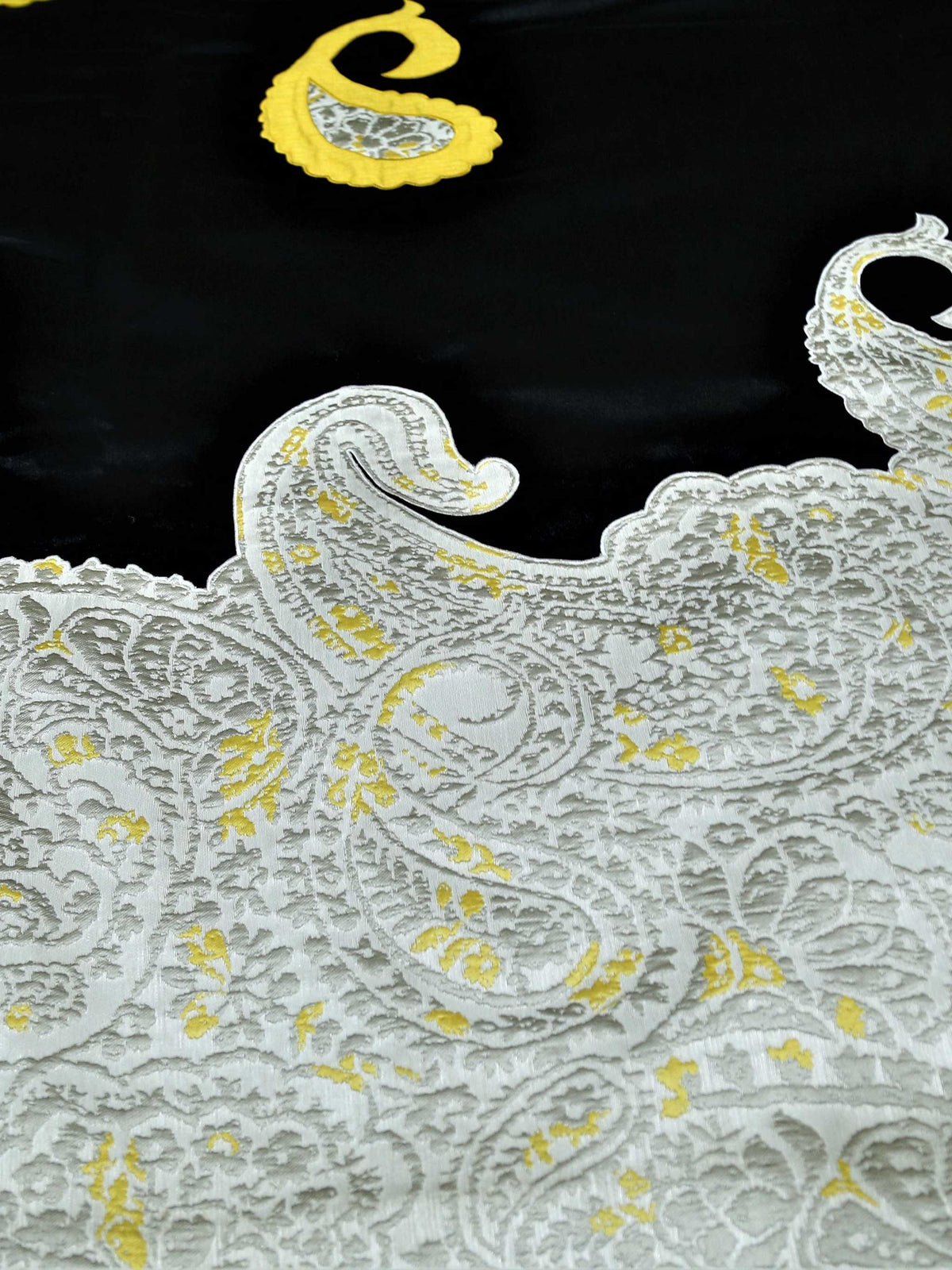 Close-up of ivory brocade paisley border scalloped against black silk