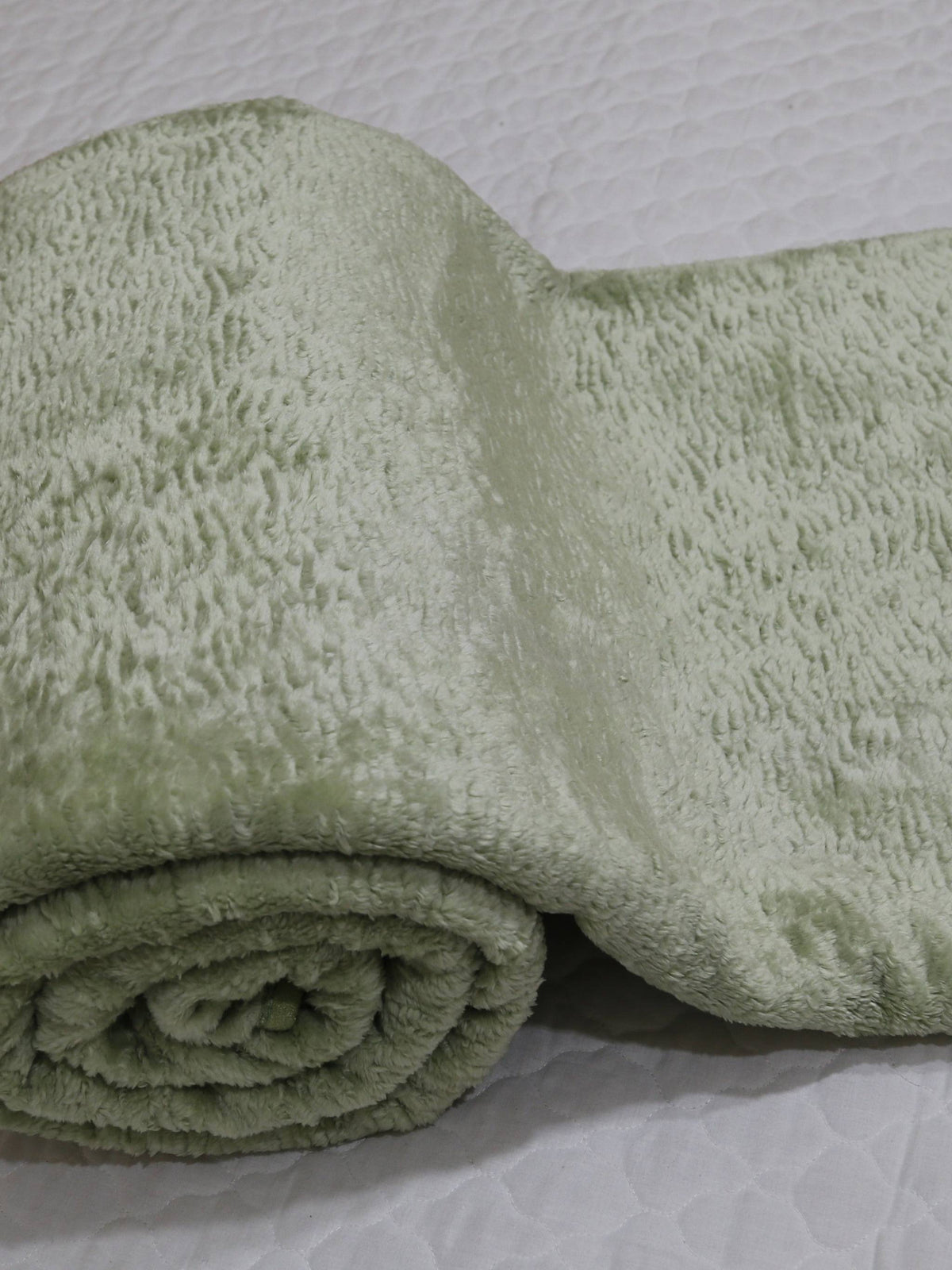 Rolled pale sage green Monaco blanket showing its soft fur-finish pile