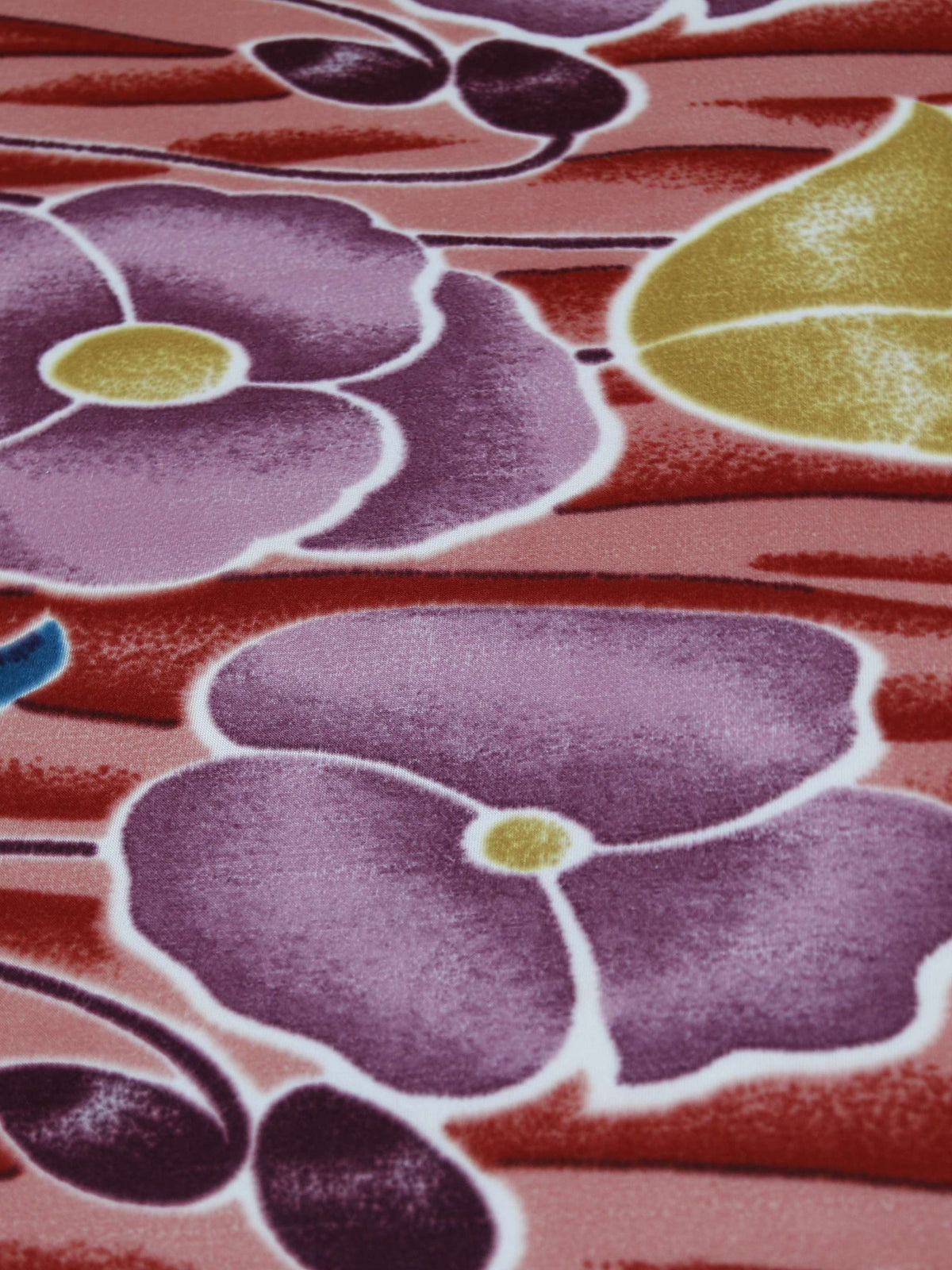 Close-up of the coral-red blanket's mauve-purple poppy floral print