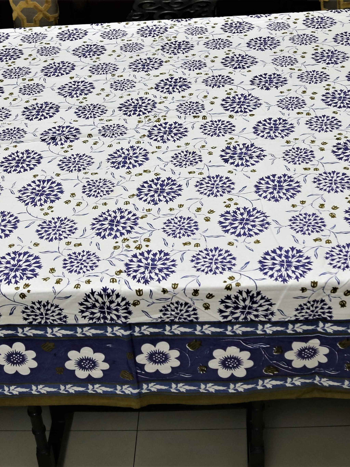 White oval table cover with a navy-blue dahlia and pompom floral print and a navy border with white flowers