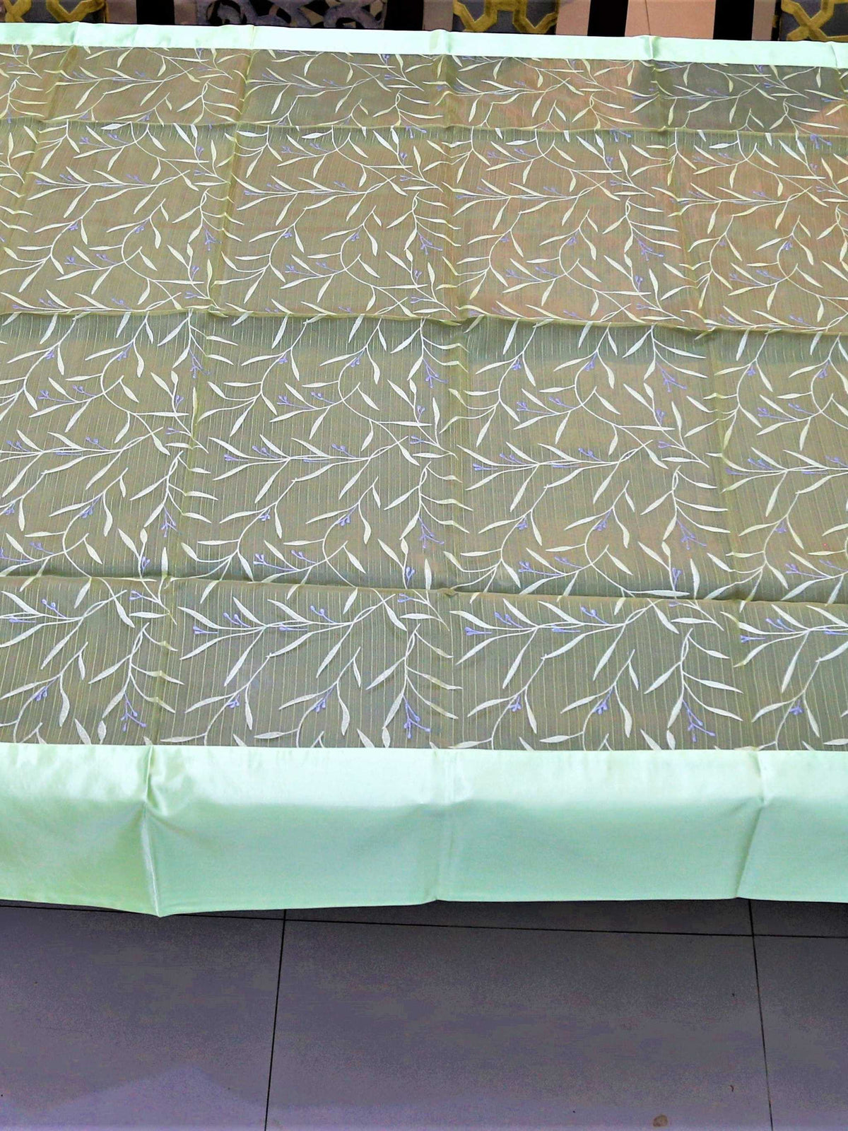Olive-green table cover with a white and silver embroidered leaf-and-vine pattern and a pale mint-green satin border