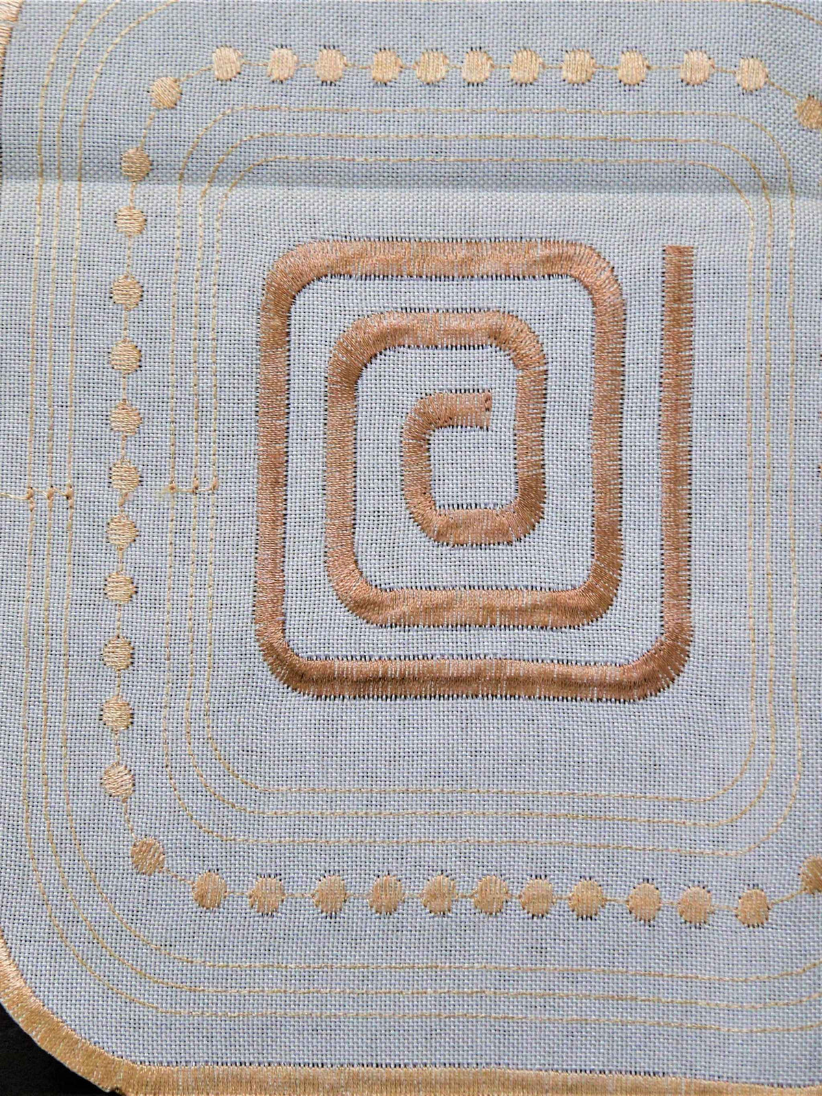 White-ivory table cover with a geometric cutwork square pattern and brown scroll motifs inside each square