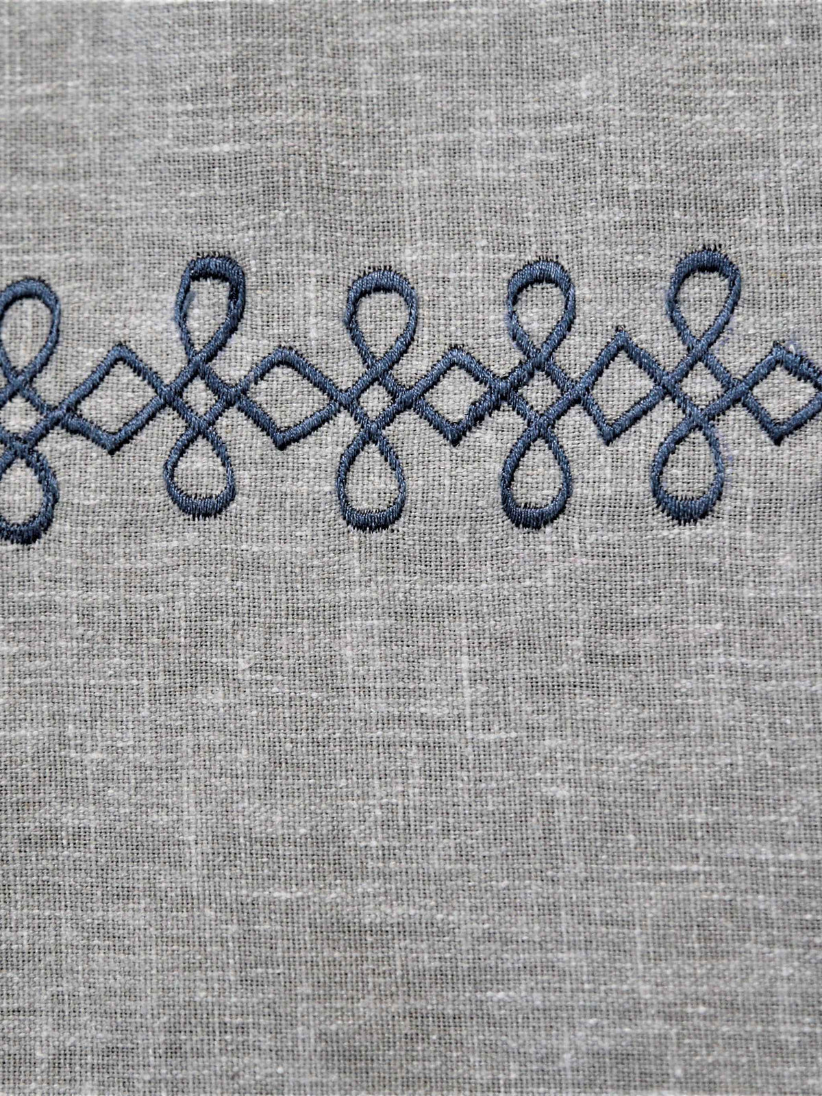 Light grey linen table cover with a navy embroidered scallop-chain border pattern