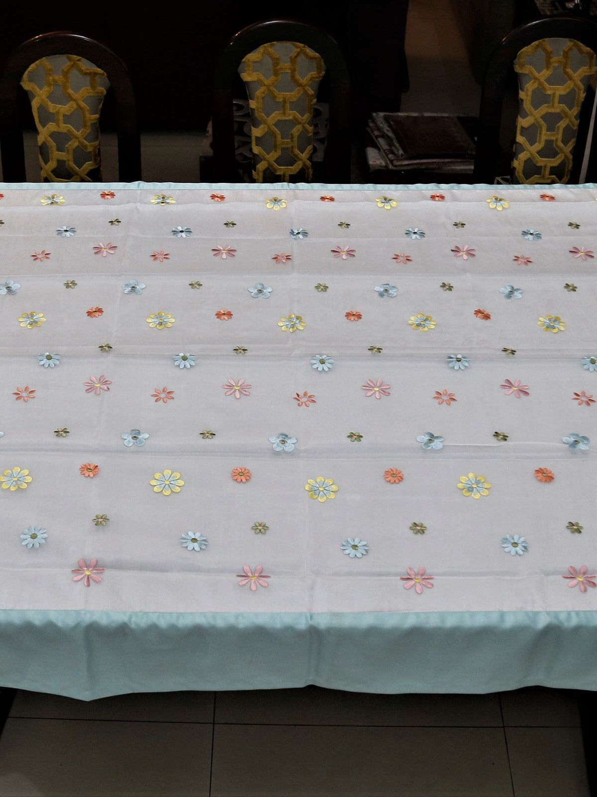 White table cover with a sequinned multicolour daisy dot pattern and a solid sea-green satin border