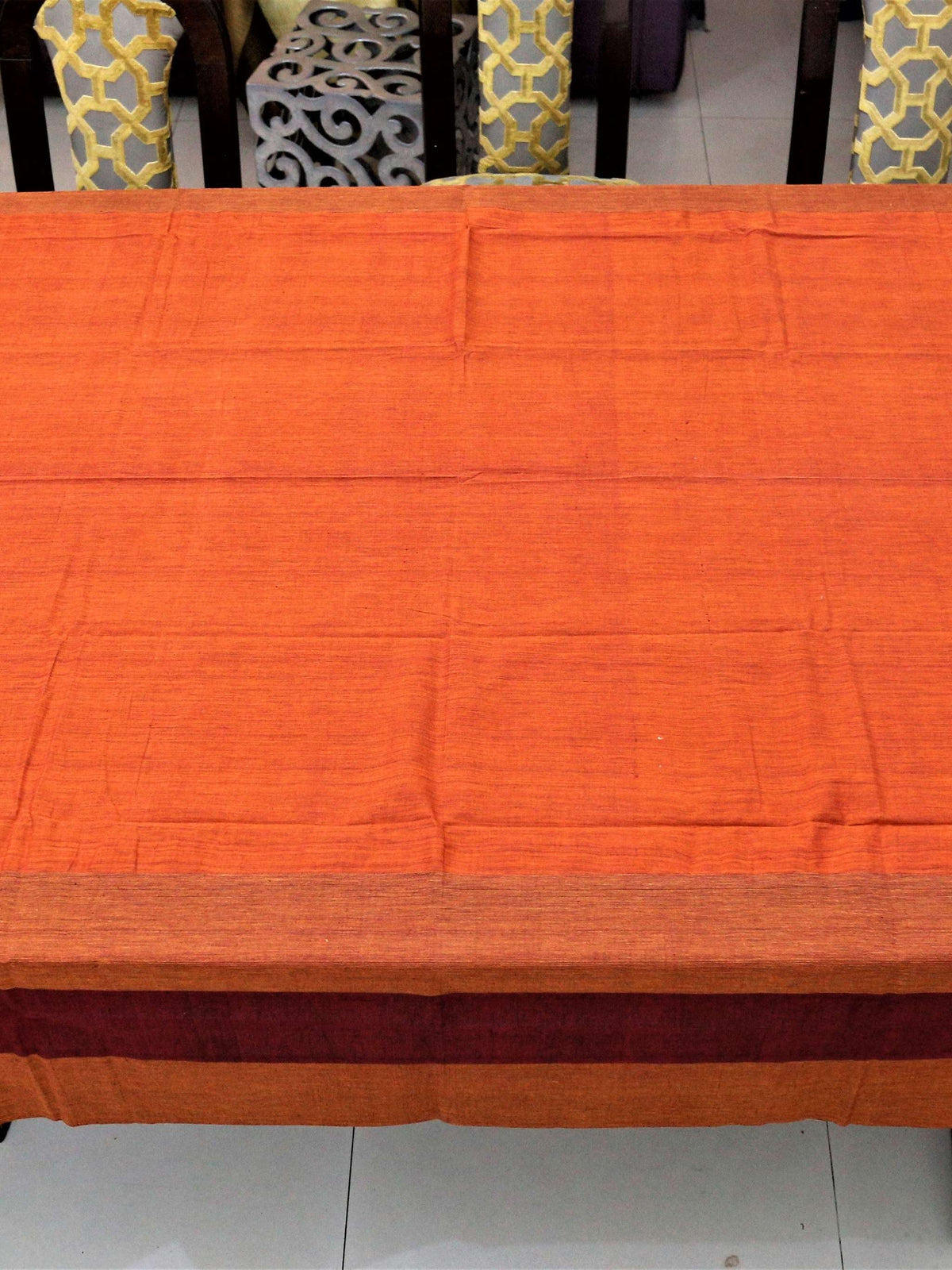 Solid rust-orange table cover with a maroon and rust horizontal striped border