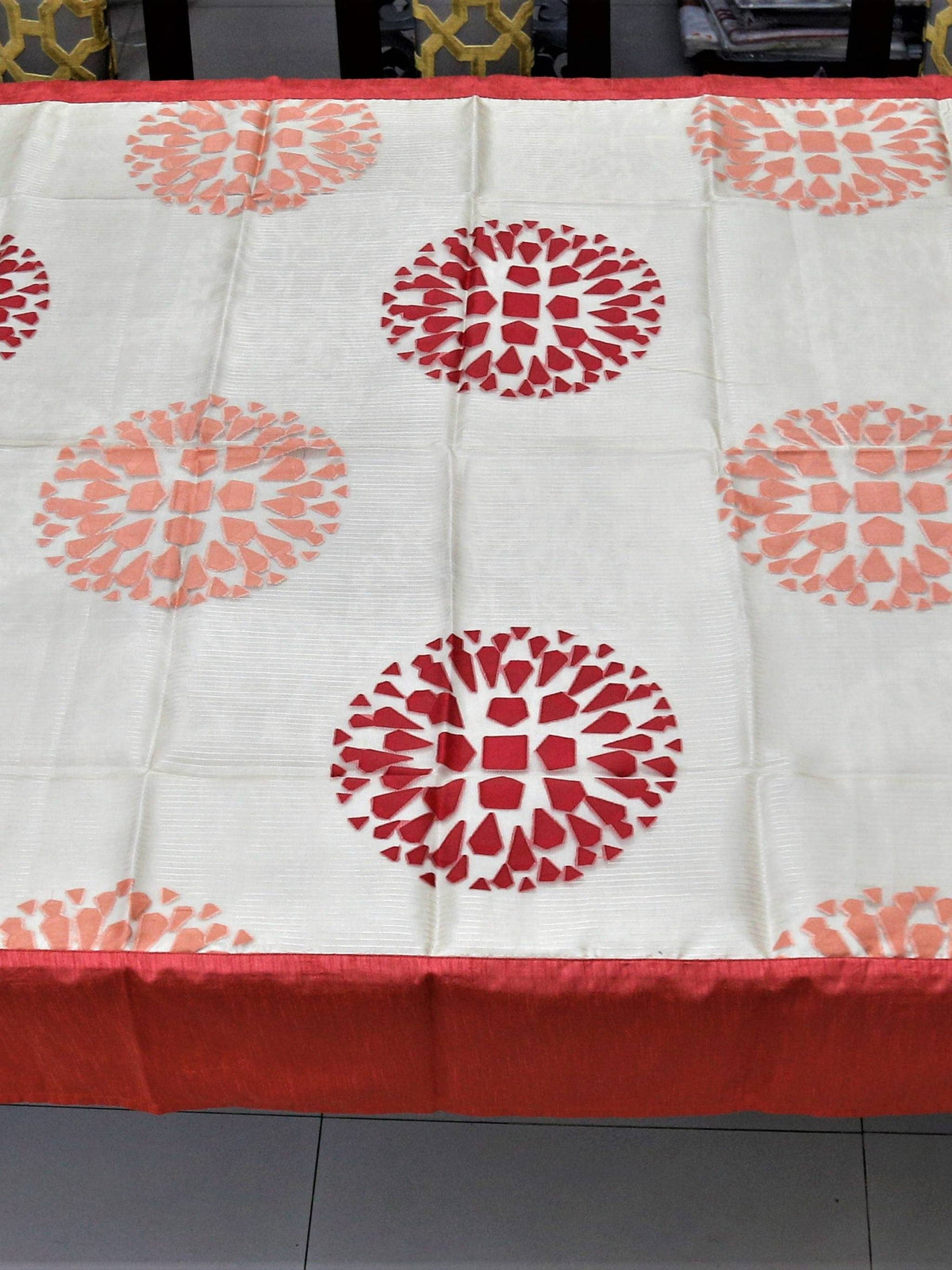 Cream table cover with a cutwork circular floral medallion pattern and a solid gajri-red border