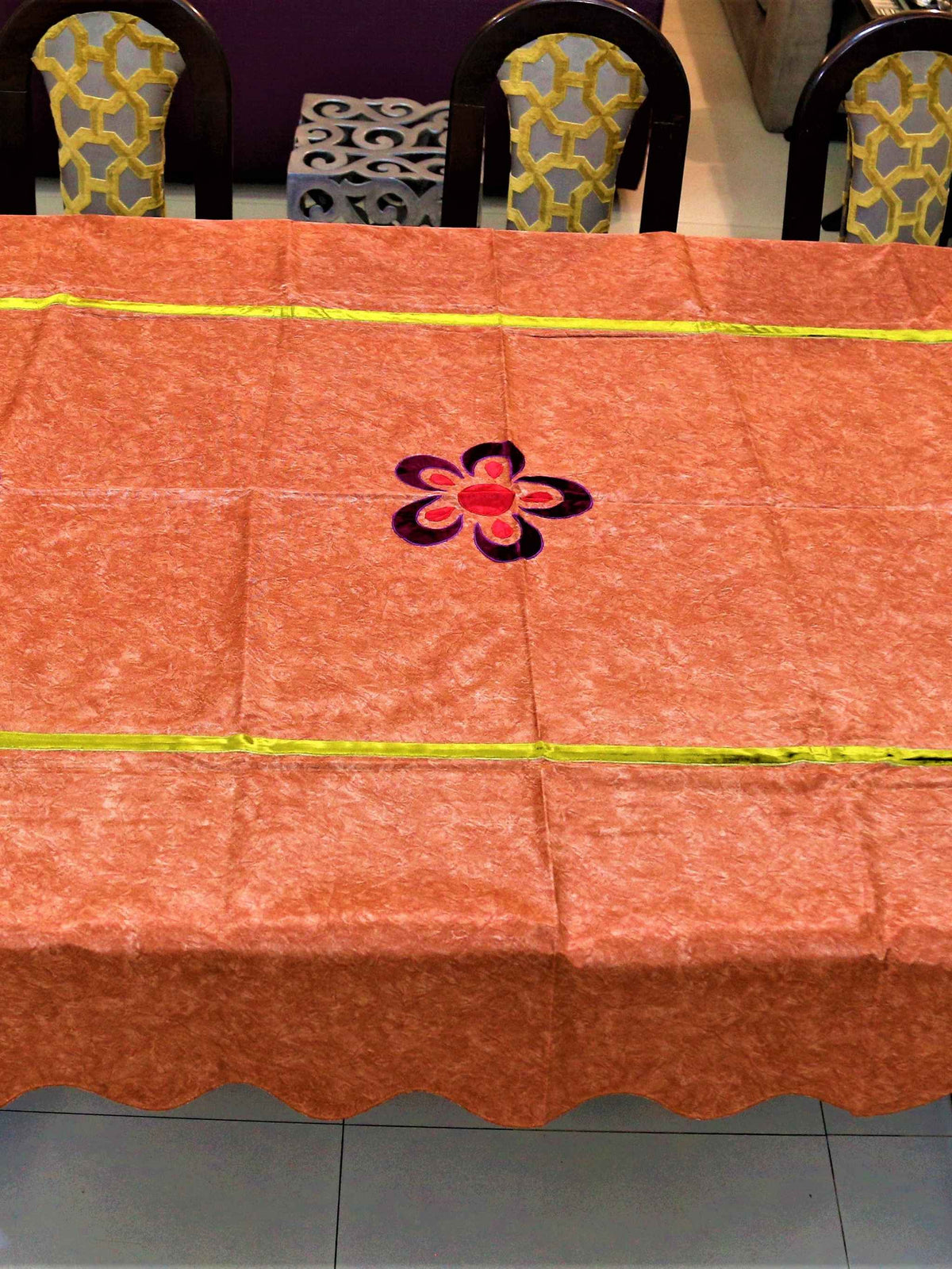Rust-orange velvet-look table cover with purple and pink flower appliqué motifs and a lime-green piped seam