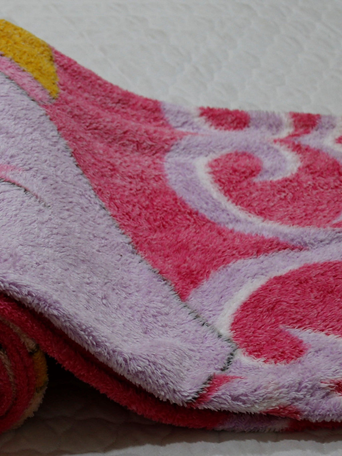 Close-up of the pink and lilac blanket's scroll-heart border pattern