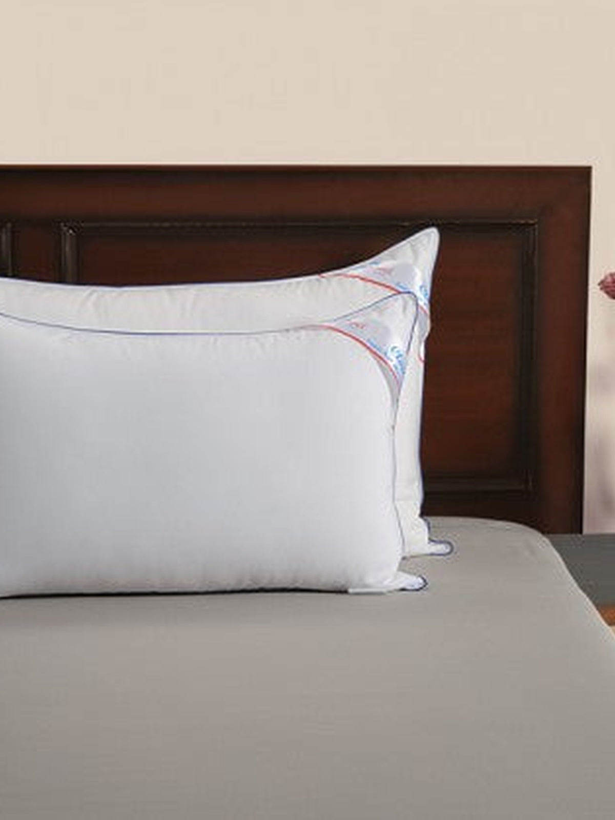Two Homescapes Cloud pillows on a made bed against a dark wooden headboard