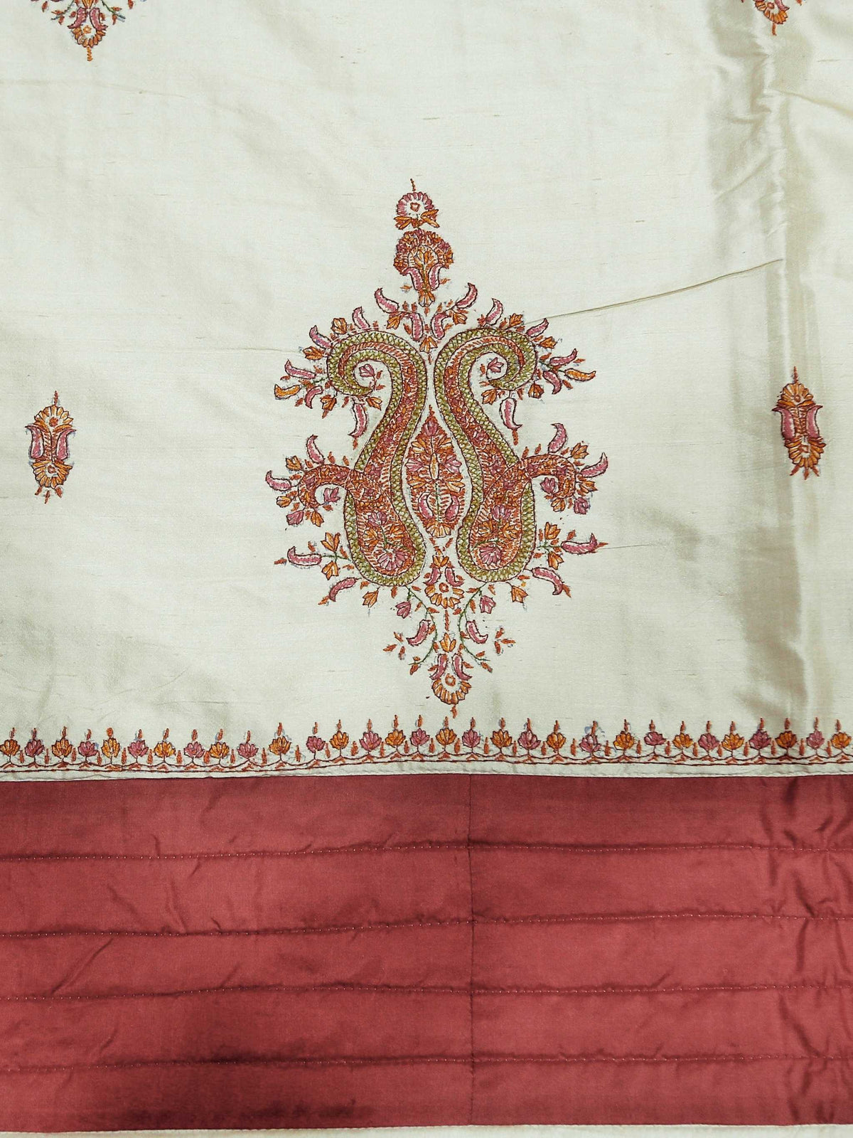 Close-up of the cream silk fabric with a maroon-gold paisley medallion embroidery and rust pleated border
