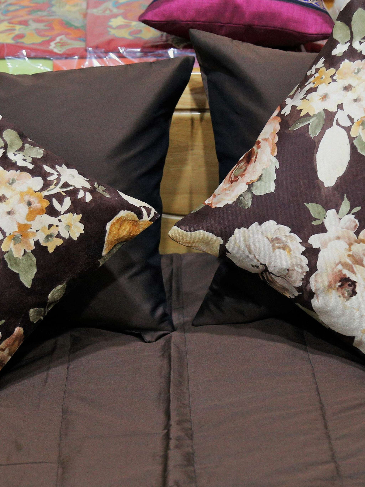 Close-up of cream and peach rose print cushion covers against brown silk