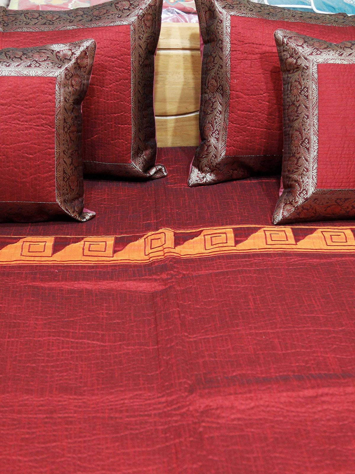 Close-up of the maroon cushion covers edged in a grey-brown brocade border