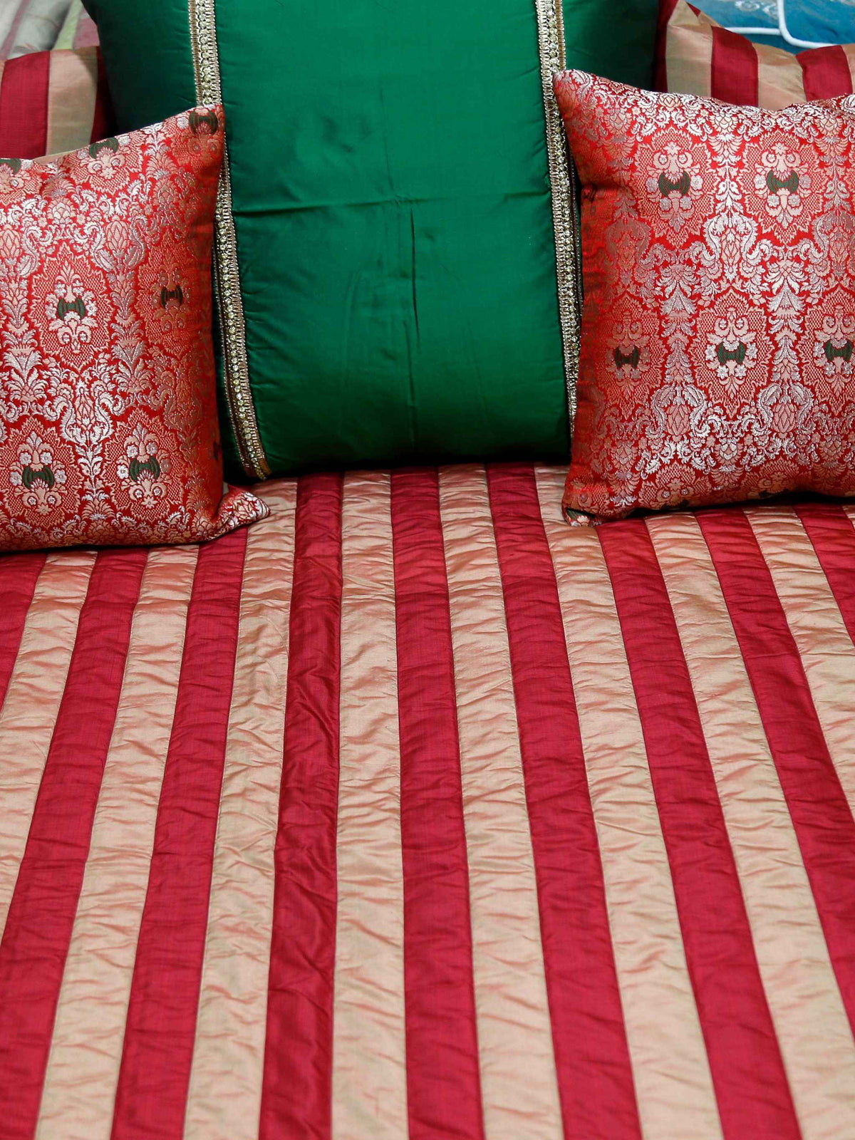 Close-up of the red damask-patterned cushion covers and green bolster pillow