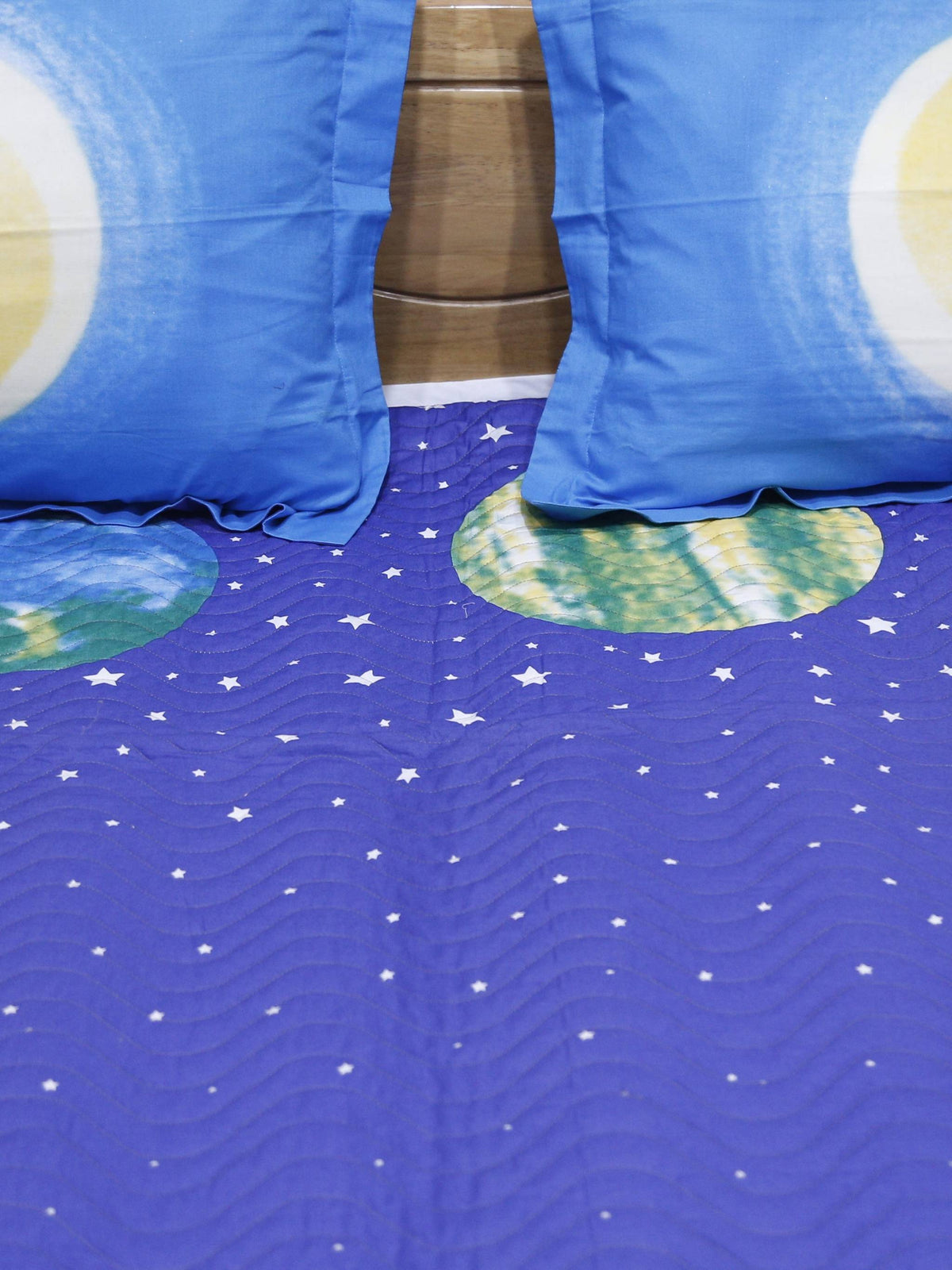 Close-up of moon print pillow covers on a starry blue children's bedcover