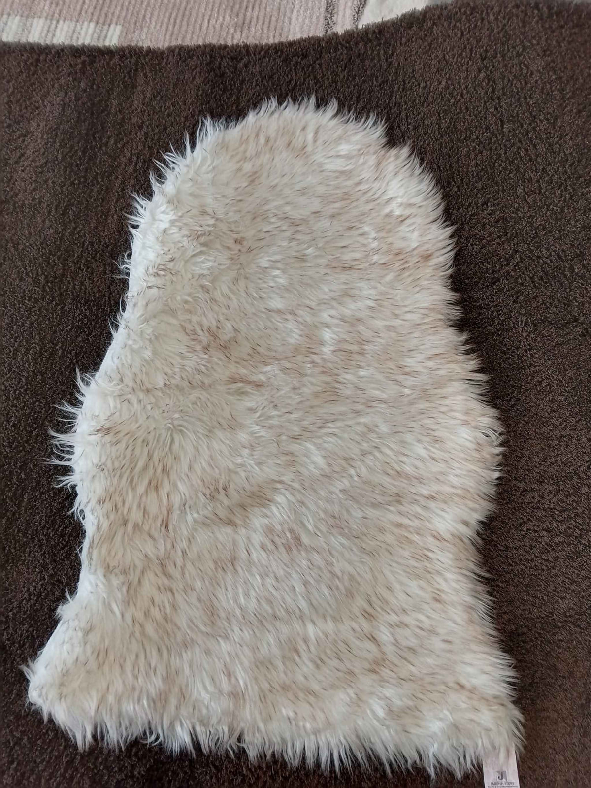 Ivory faux sheepskin bedside runner laid on a brown carpet