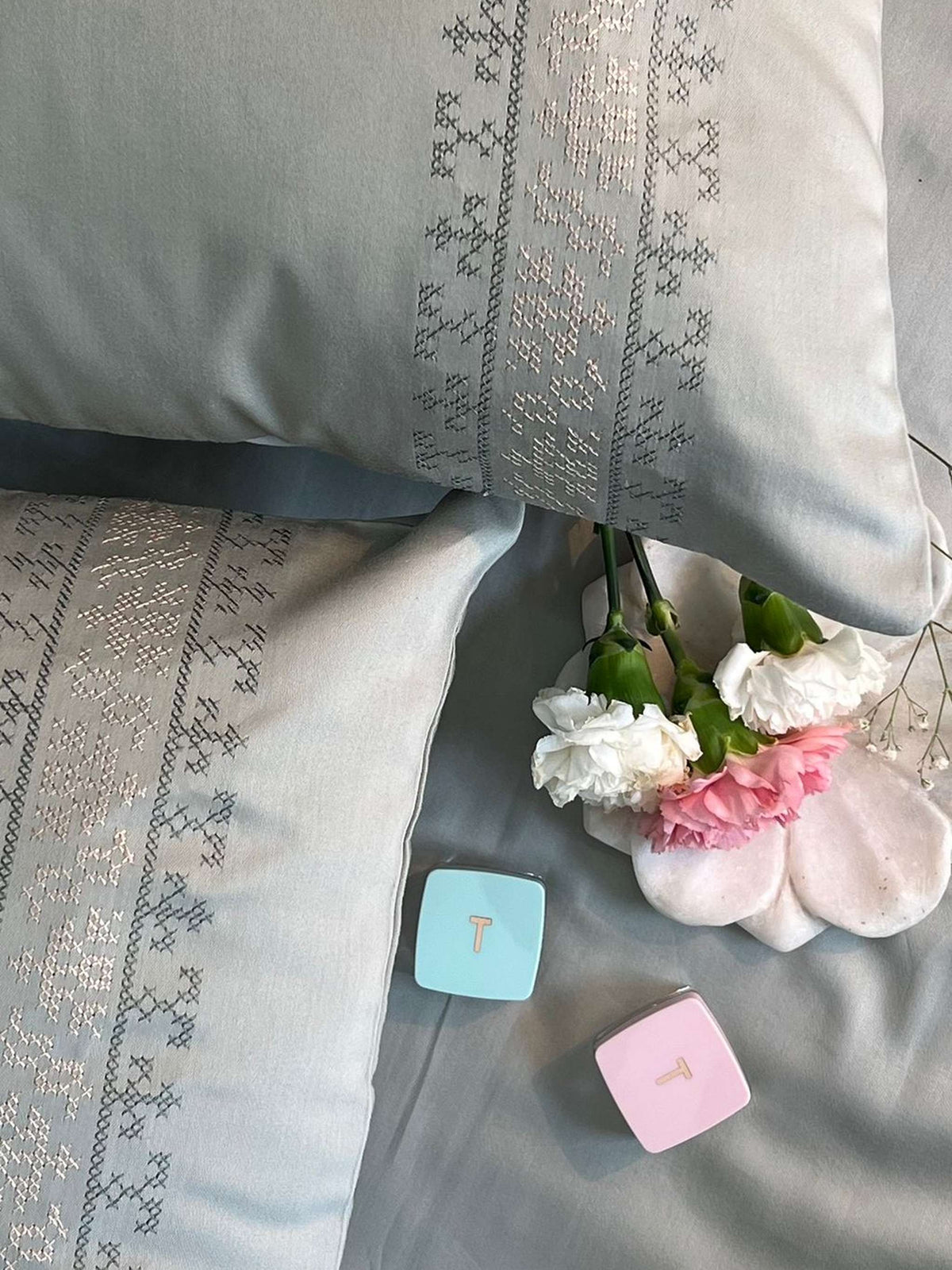 Sage green bedding with a grey and metallic cross-stitch embroidered band