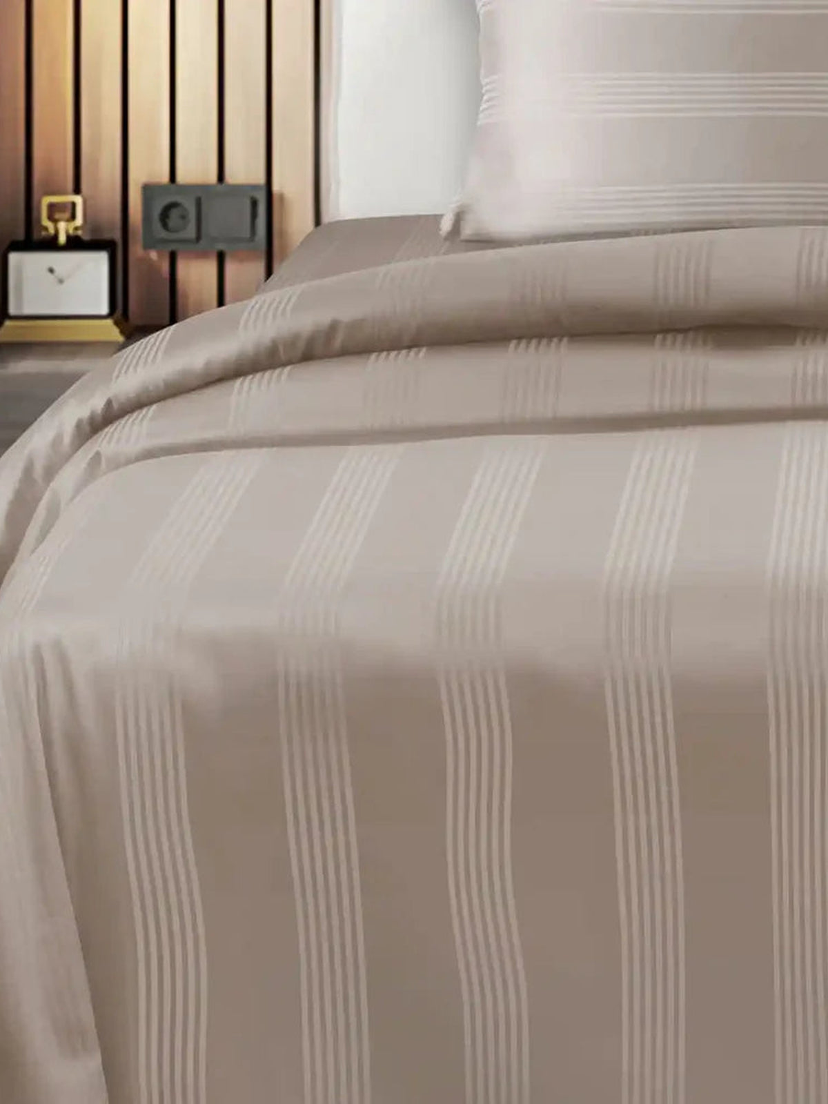 Taupe satin stripe cotton bedsheet draped over a bed with cream stripe detail
