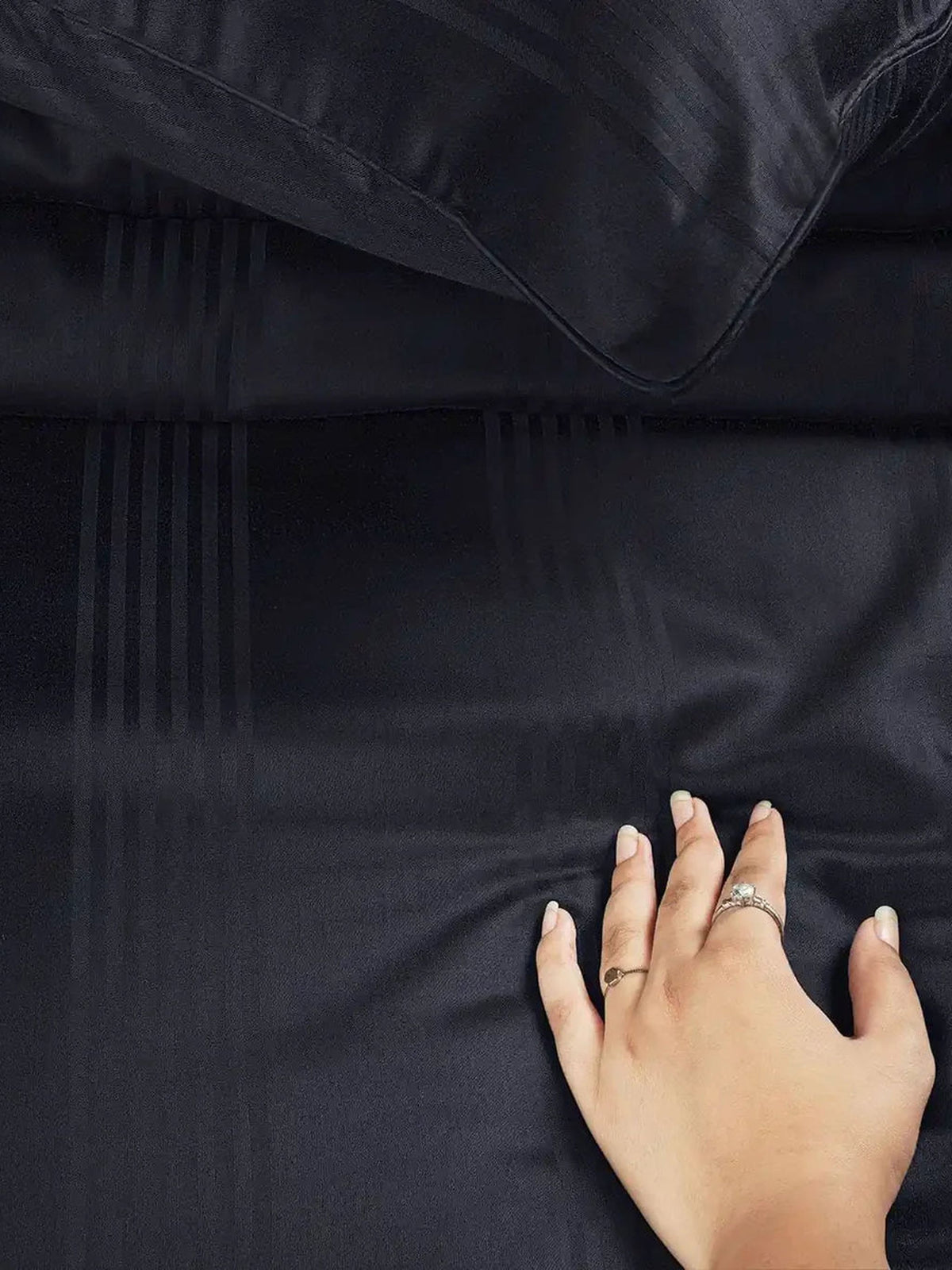 Hand resting on black satin stripe cotton to show its sheen and softness