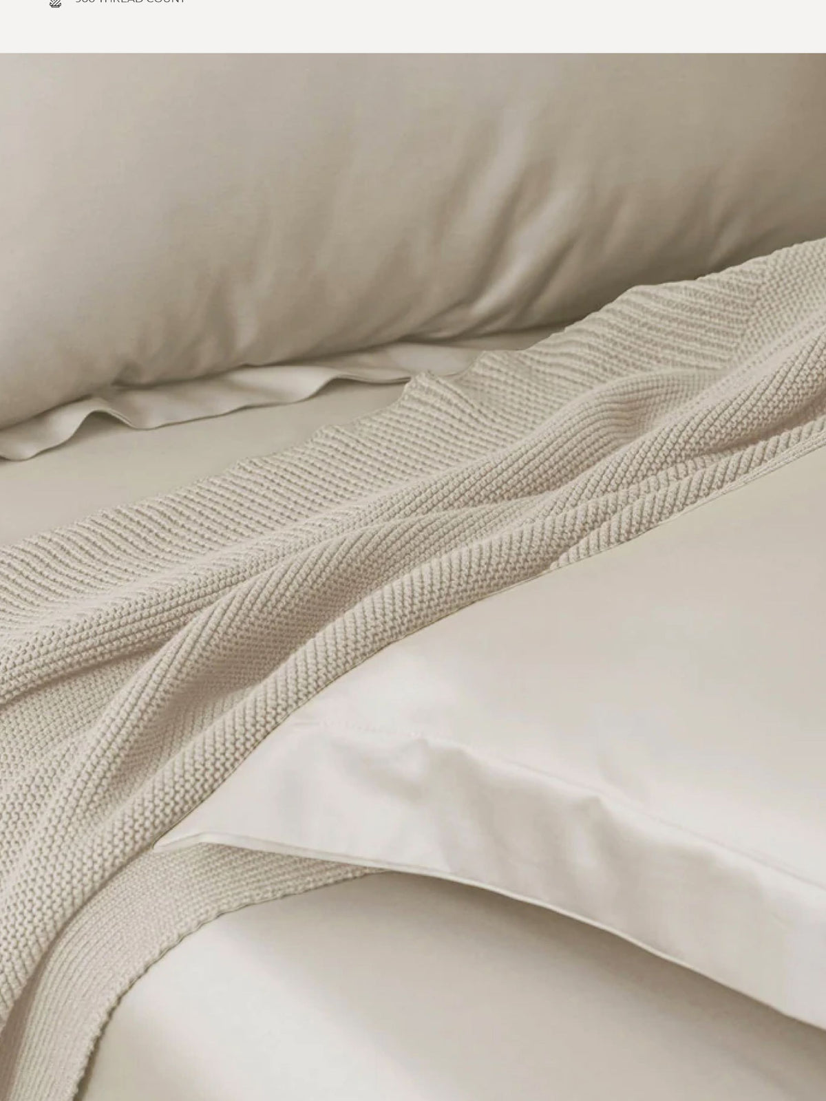 Sand beige Supima cotton bedding with a waffle throw folded across it