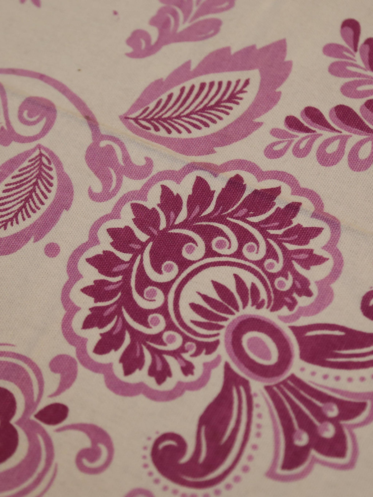 Off-white oval table cover set with a pink and purple paisley floral print, a solid mauve-pink border, and matching mauve triangle-folded napkins