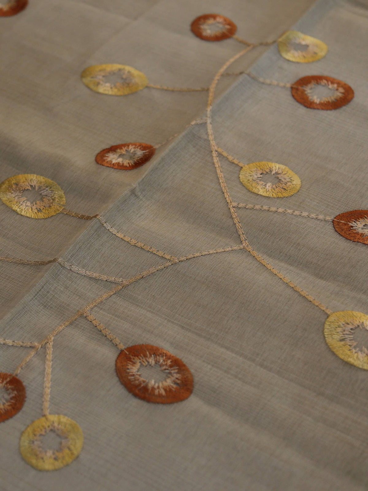 Cream oval table cover with a rust-orange and gold ring embroidery vine pattern and a solid cream border