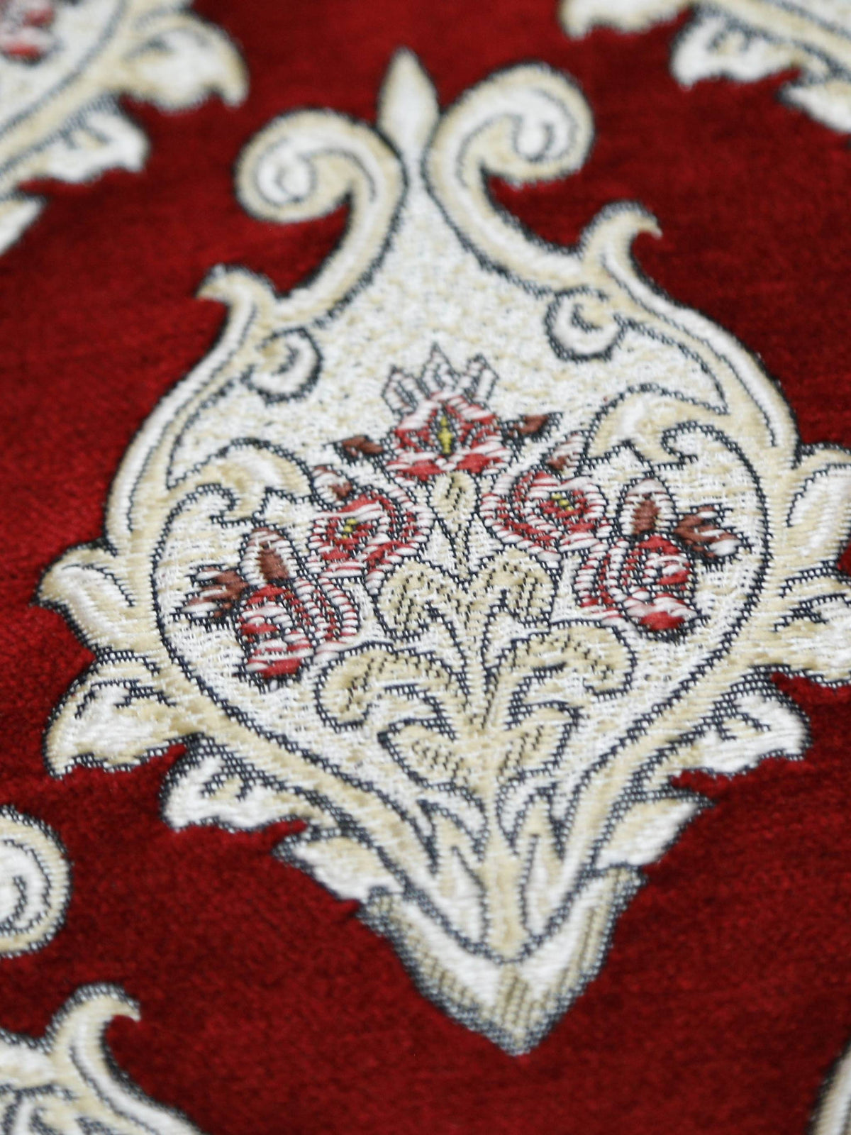 Closer crop of the red and cream damask medallion fabric on the quilted bedcover
