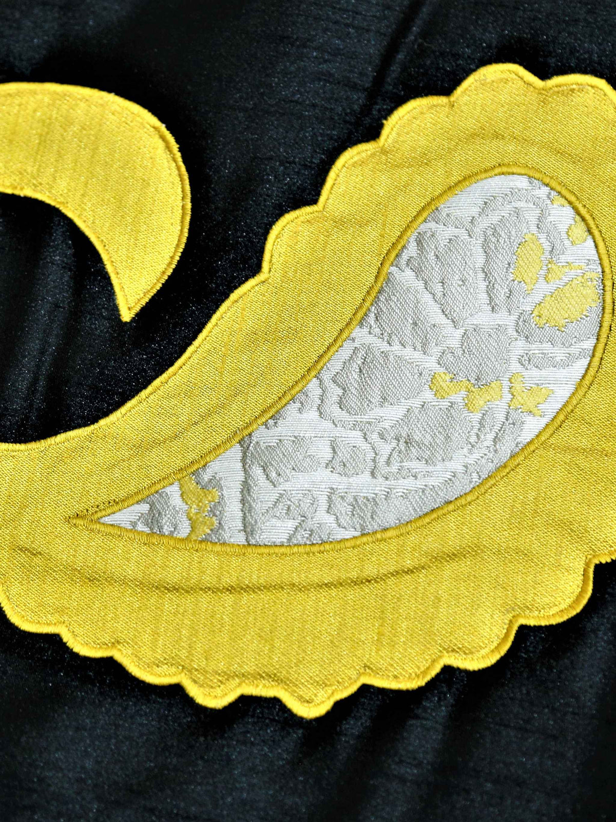 Close-up of yellow satin paisley applique with ivory brocade inlay on black silk