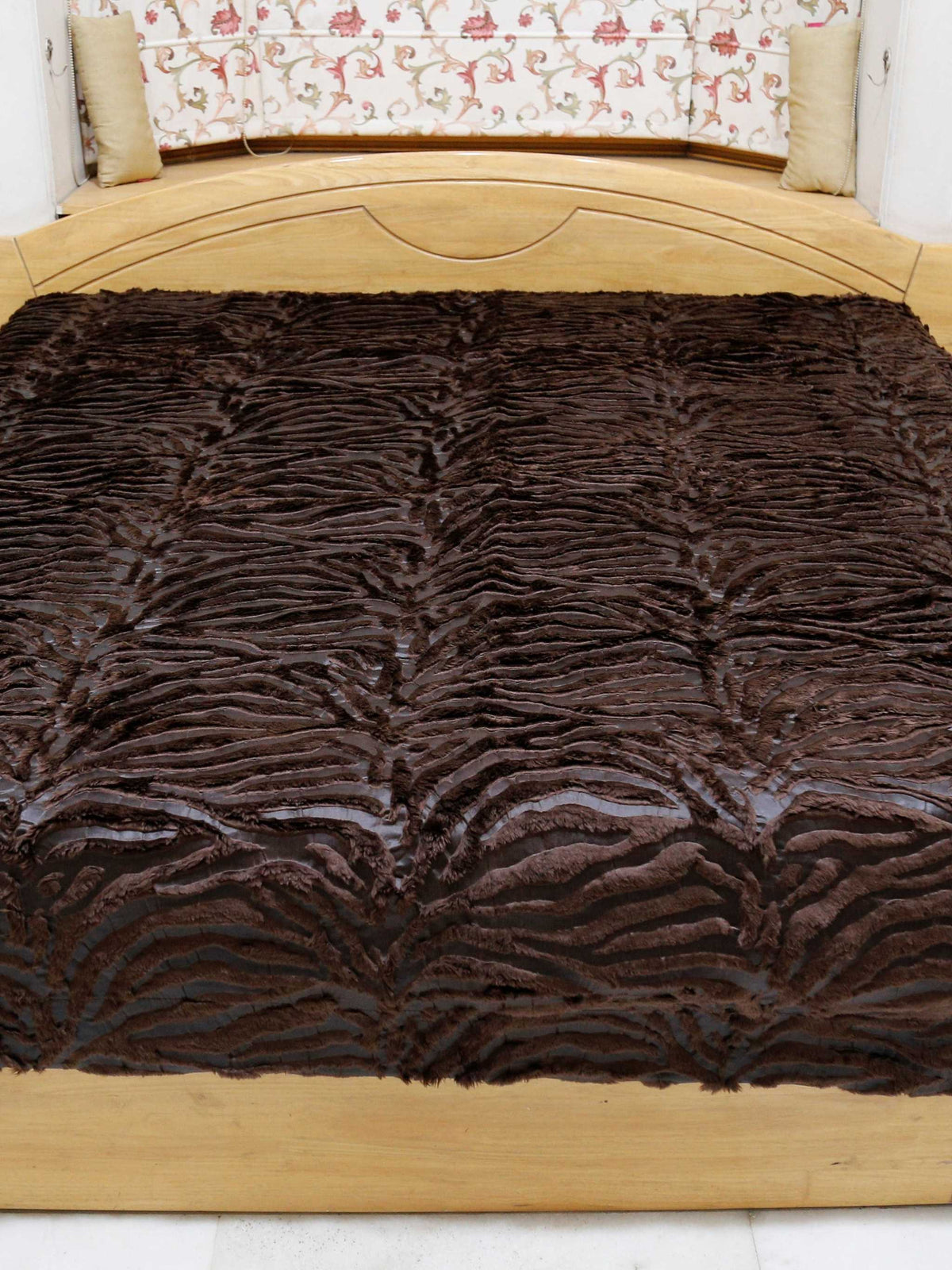 Dark chocolate-brown faux-fur blanket with a wavy zebra-stripe texture, covering a bed from the foot end