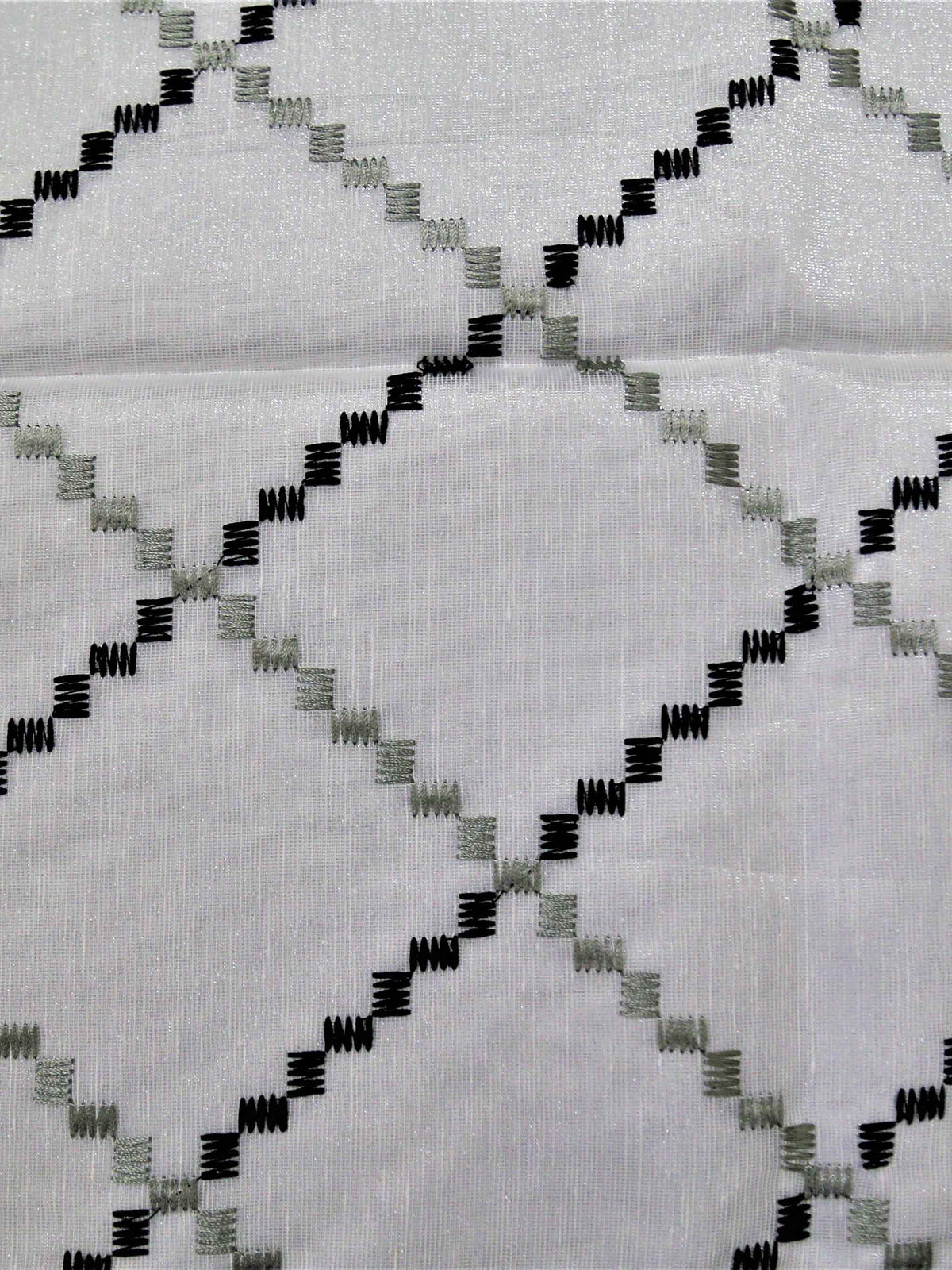 White table cover with a black and grey diamond-lattice embroidered pattern and a plain beige-tan underskirt with a black edge trim