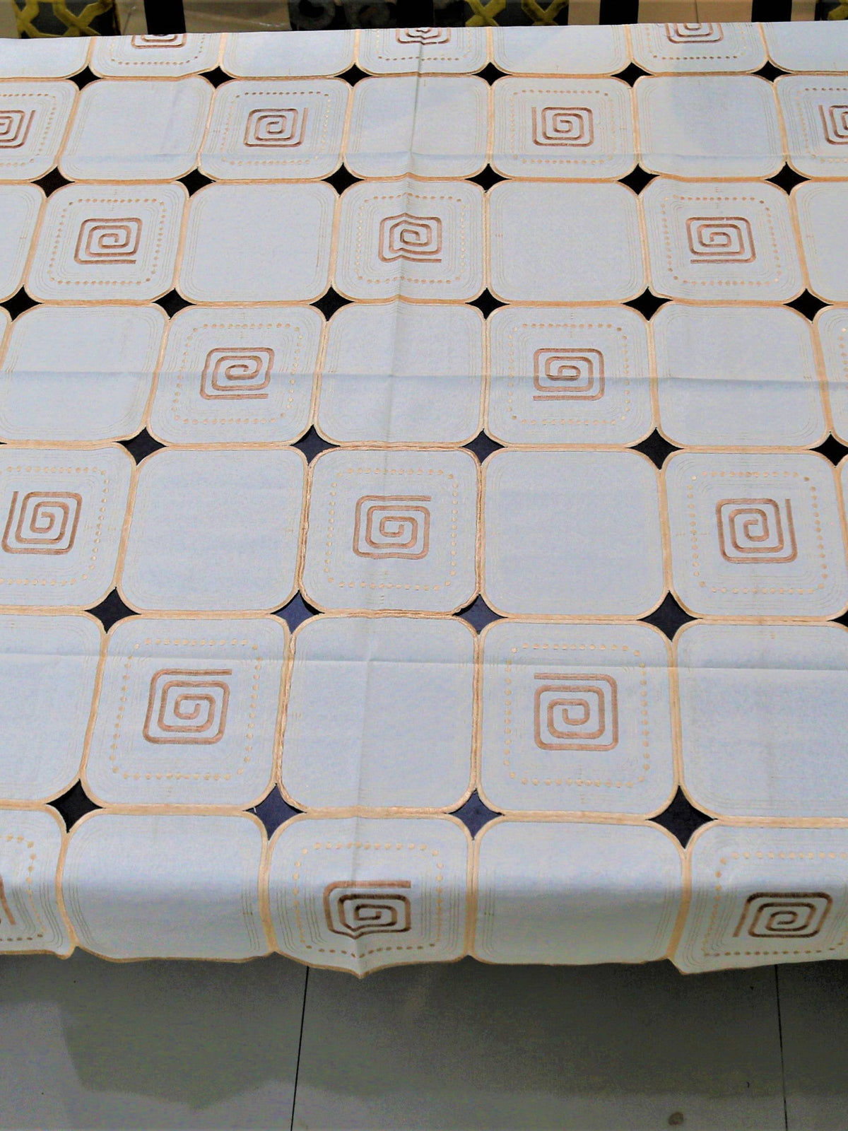 White-ivory table cover with a geometric cutwork square pattern and brown scroll motifs inside each square