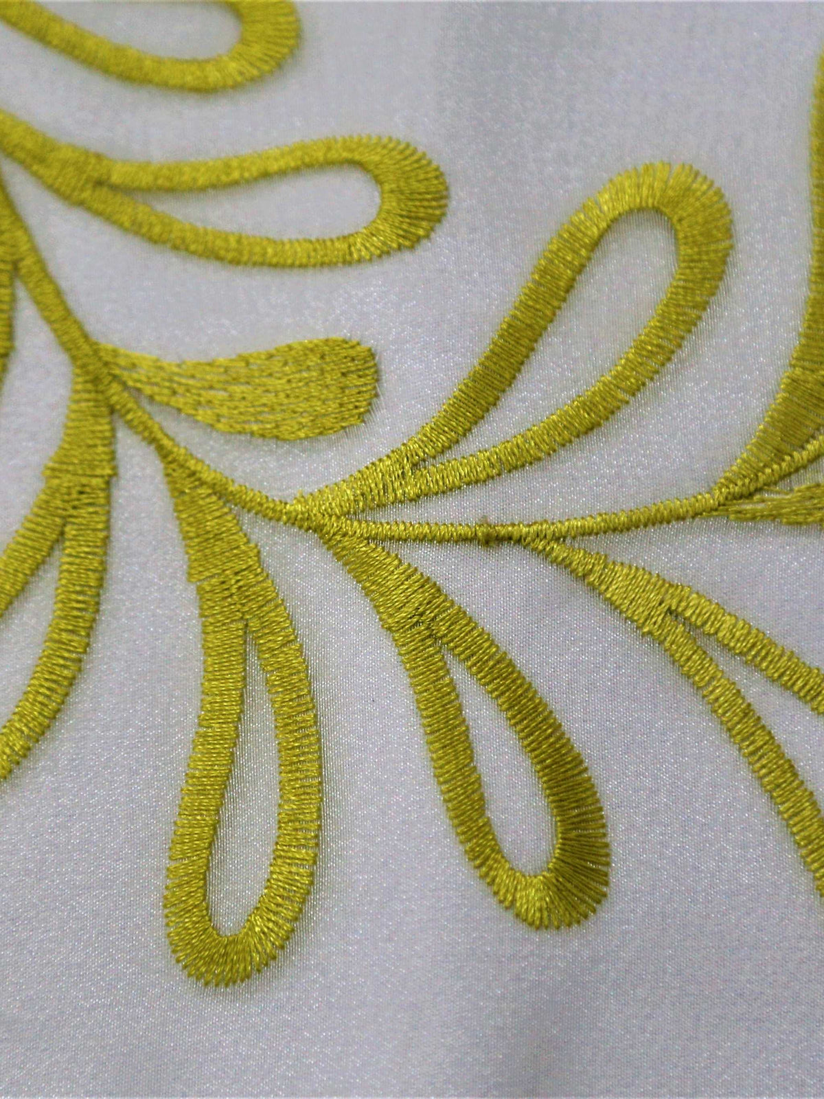 White table cover with a green and yellow embroidered fern-leaf vine pattern and a solid olive-green underskirt