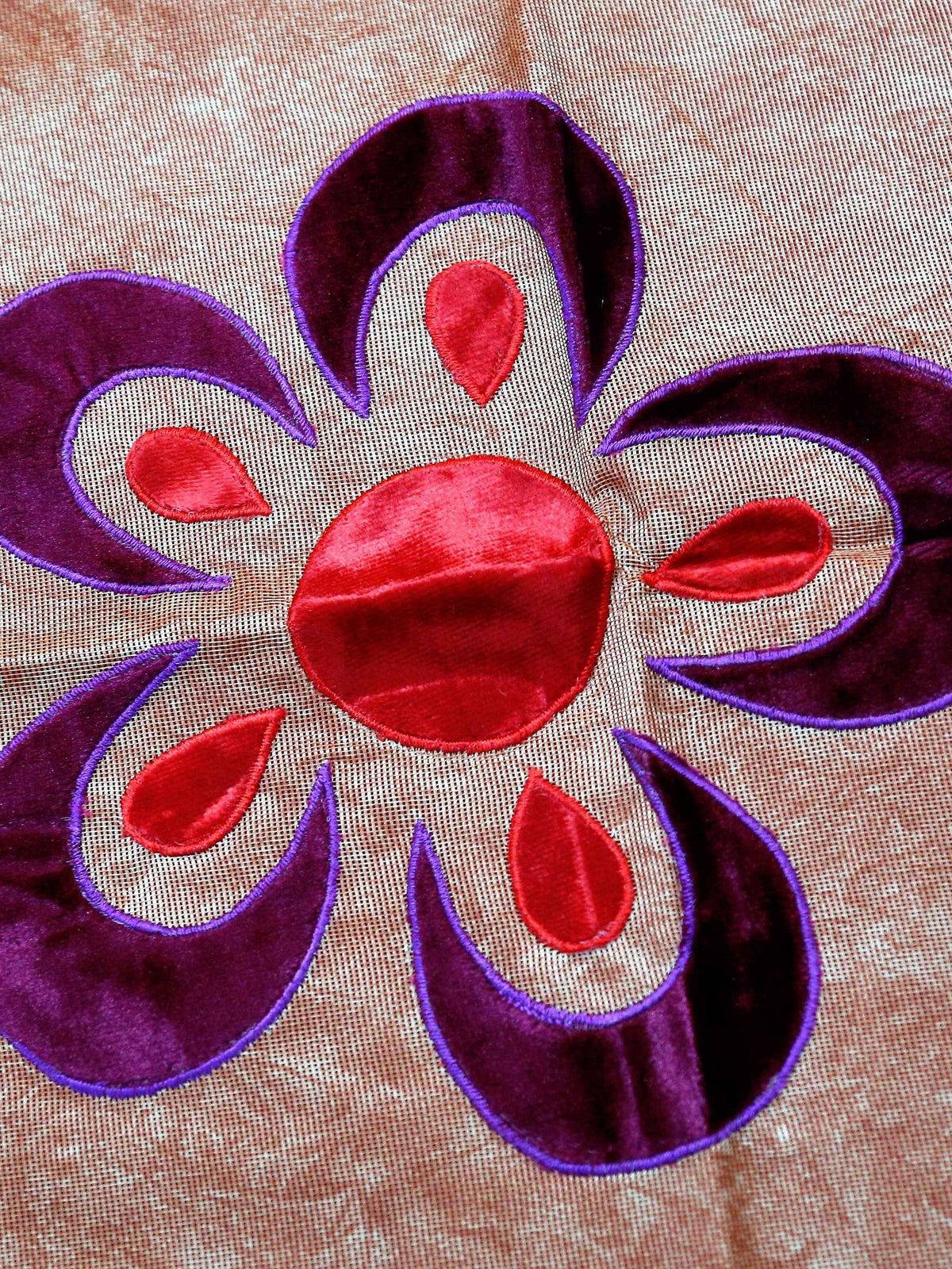 Rust-orange velvet-look table cover with purple and pink flower appliqué motifs and a lime-green piped seam
