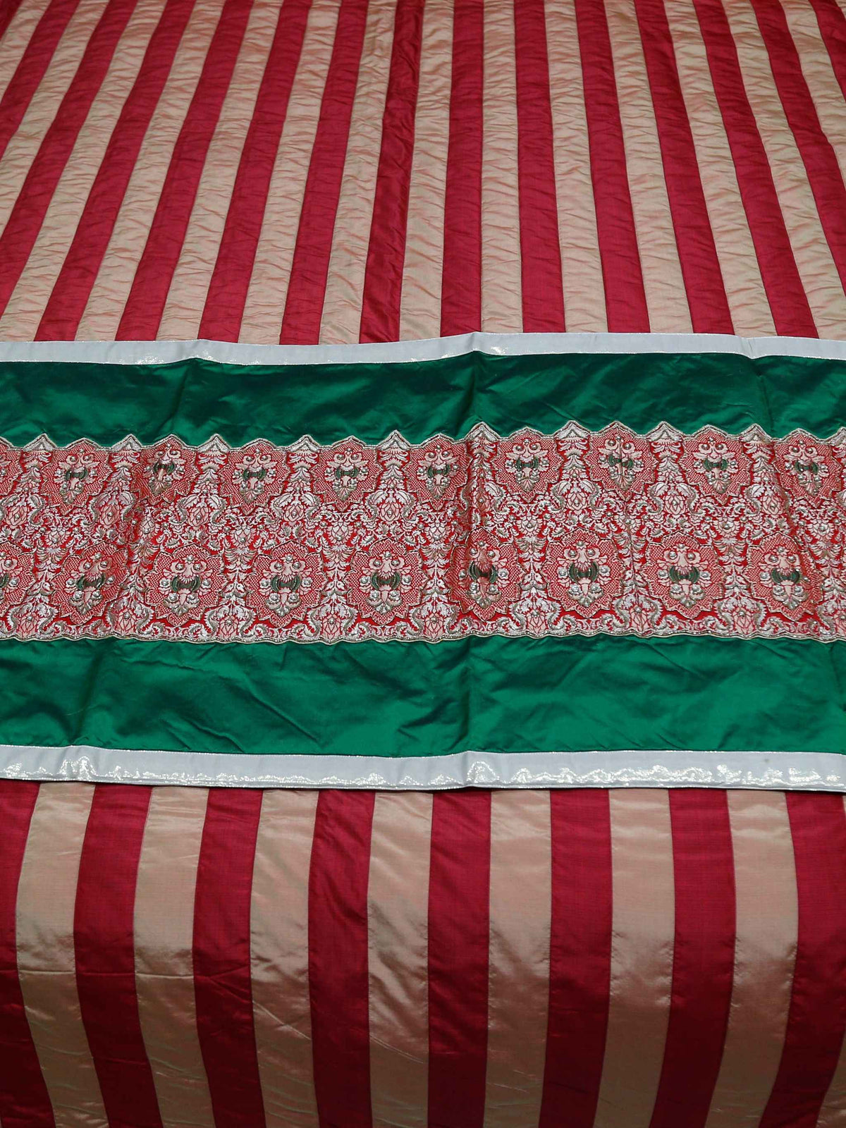 Close-up of the green and red brocade runner fabric with a cream lace-effect border
