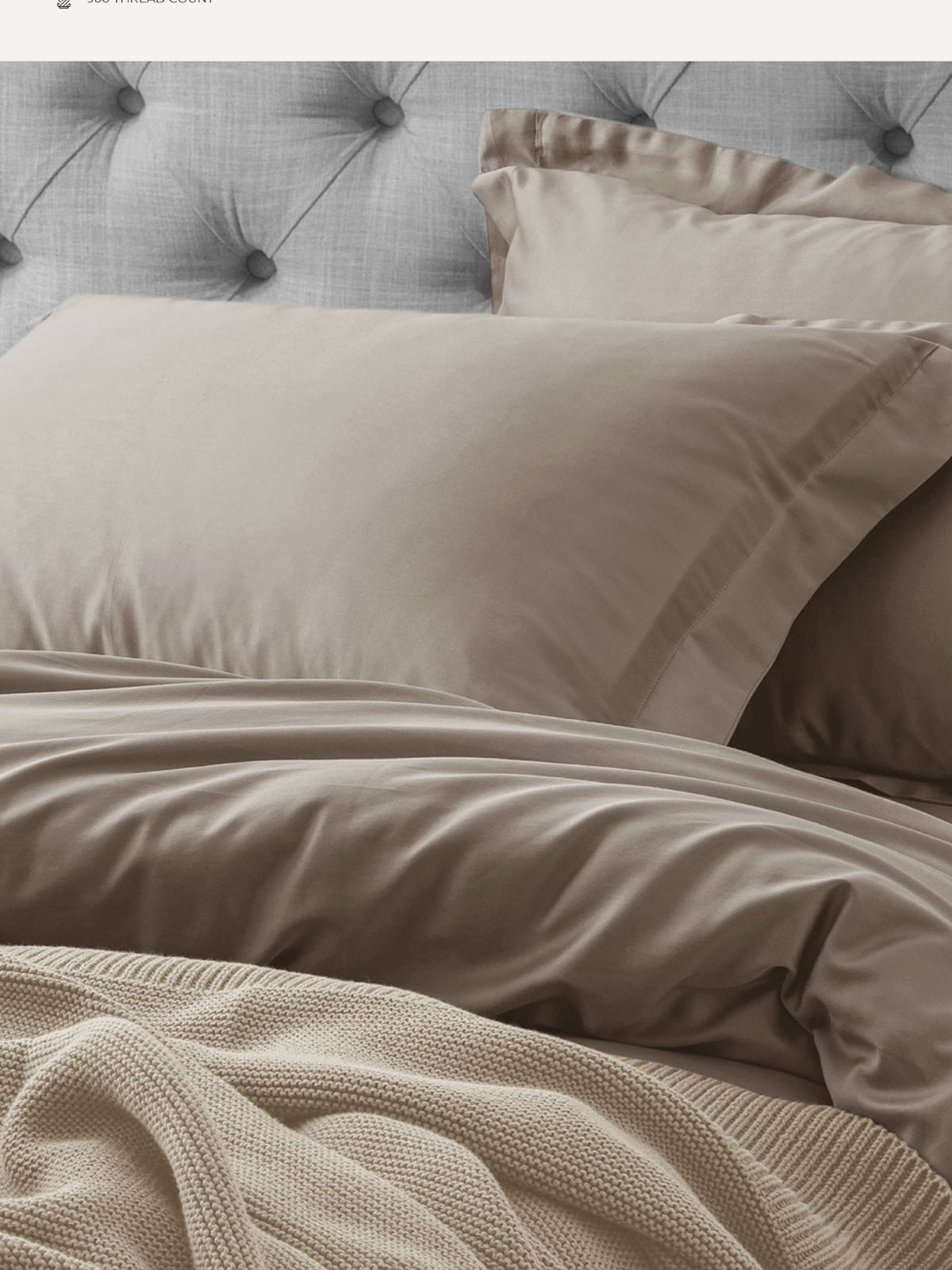 Taupe Supima cotton bedding with oxford pillows on a tufted headboard