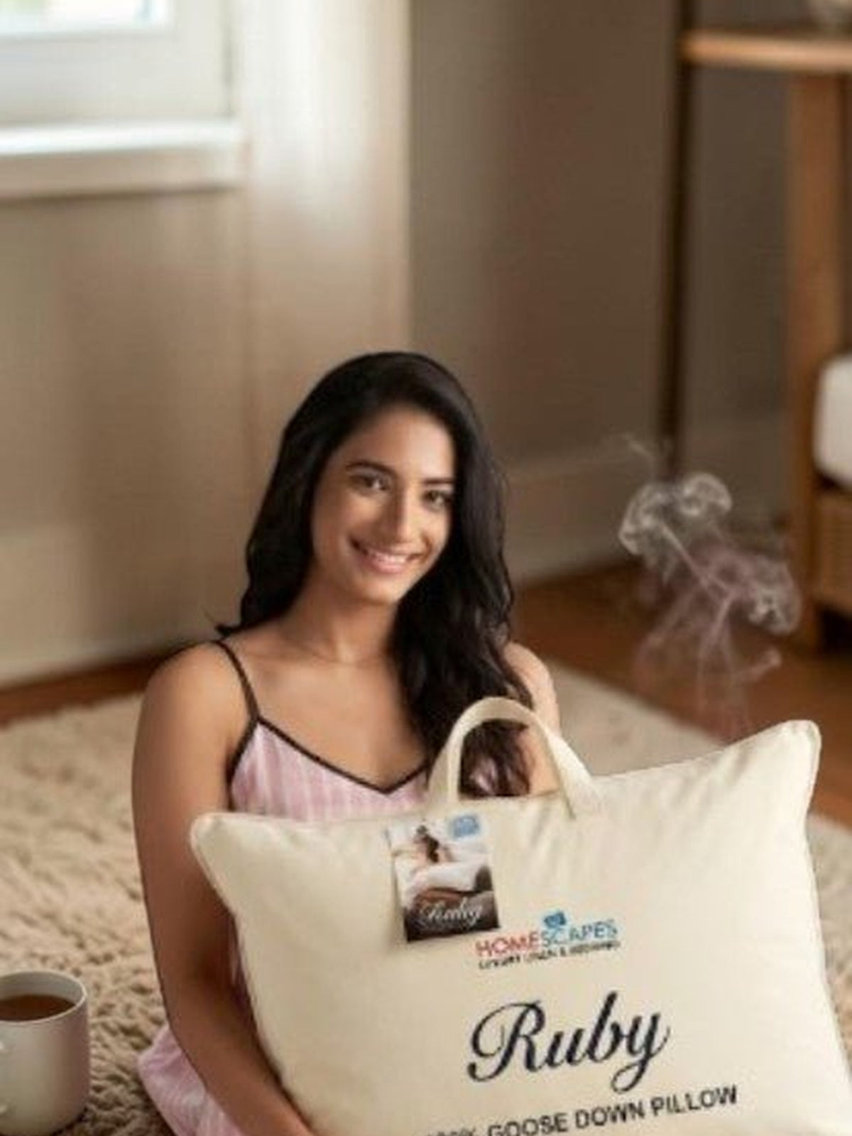 Woman holding the Ruby goose down pillow in its branded carry bag