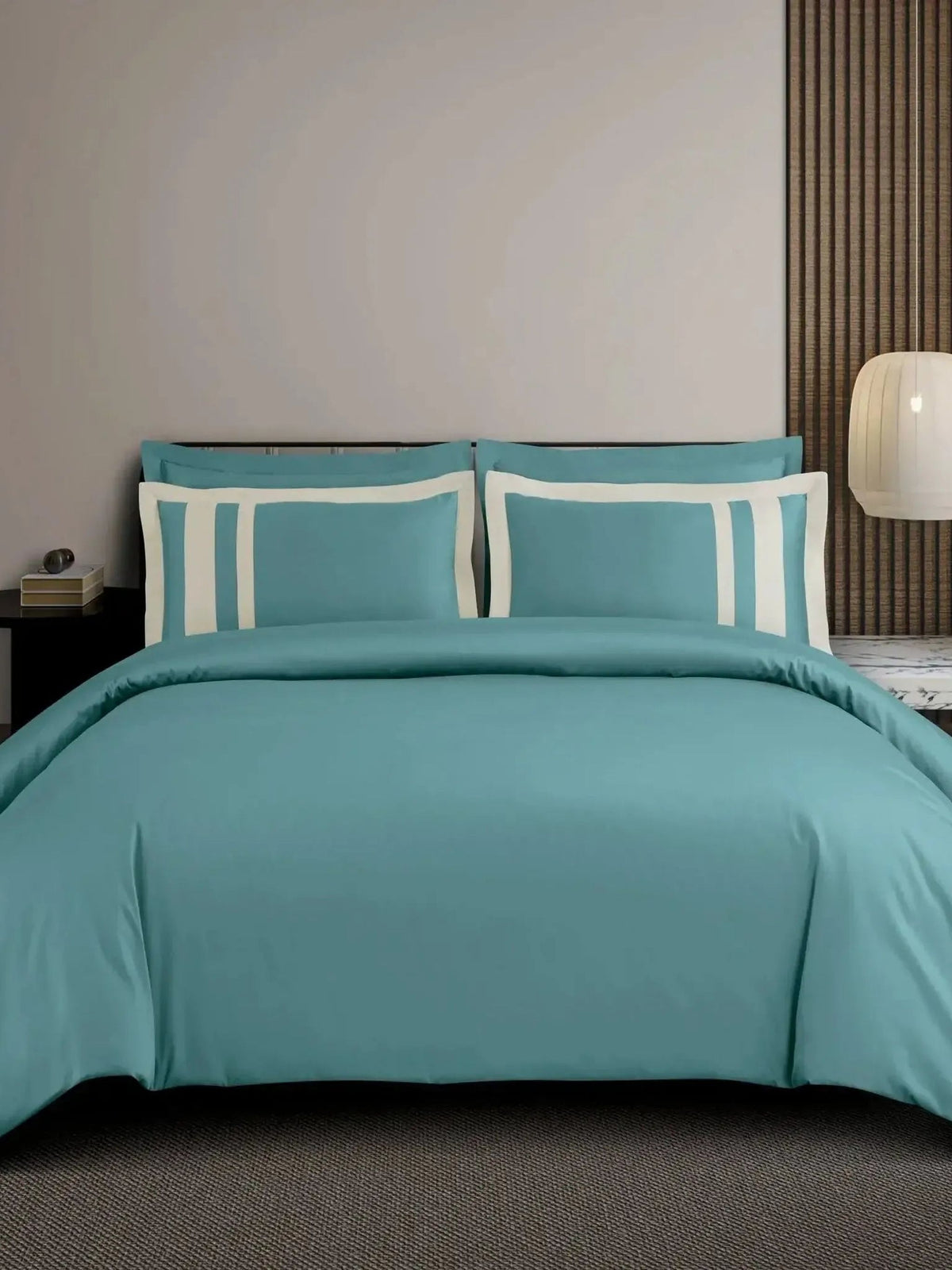 Teal-green cotton bedsheet set with a white block-stripe border on the pillow covers, styled on a bed
